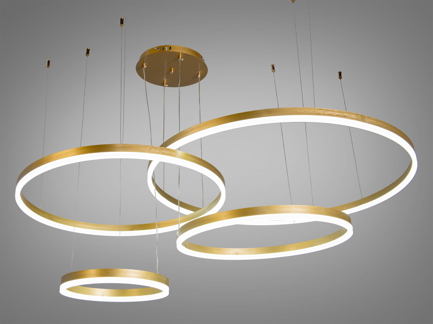 Підвісний світильник з пультом дистанційного керування, що дозволяє регулювати освітлення, має три золоті кільця.