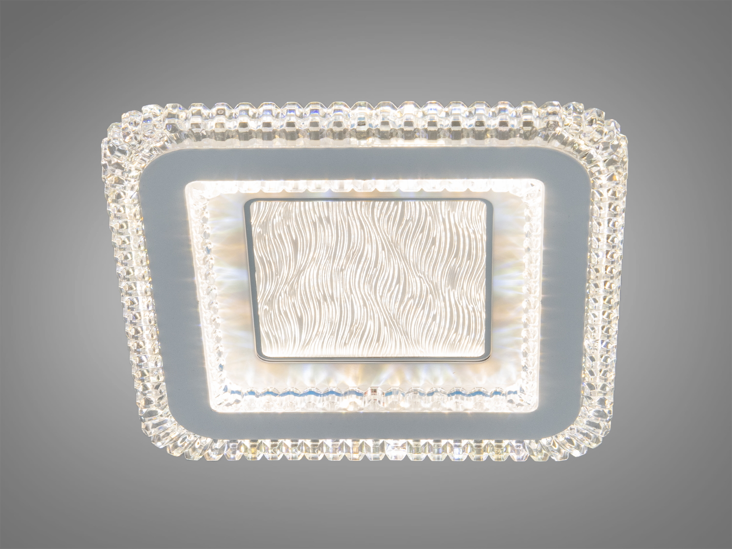 Стельова лампа квадратної форми з хвилястим візерунком, обрамлена прозорими краями для створення затишного освітлення.