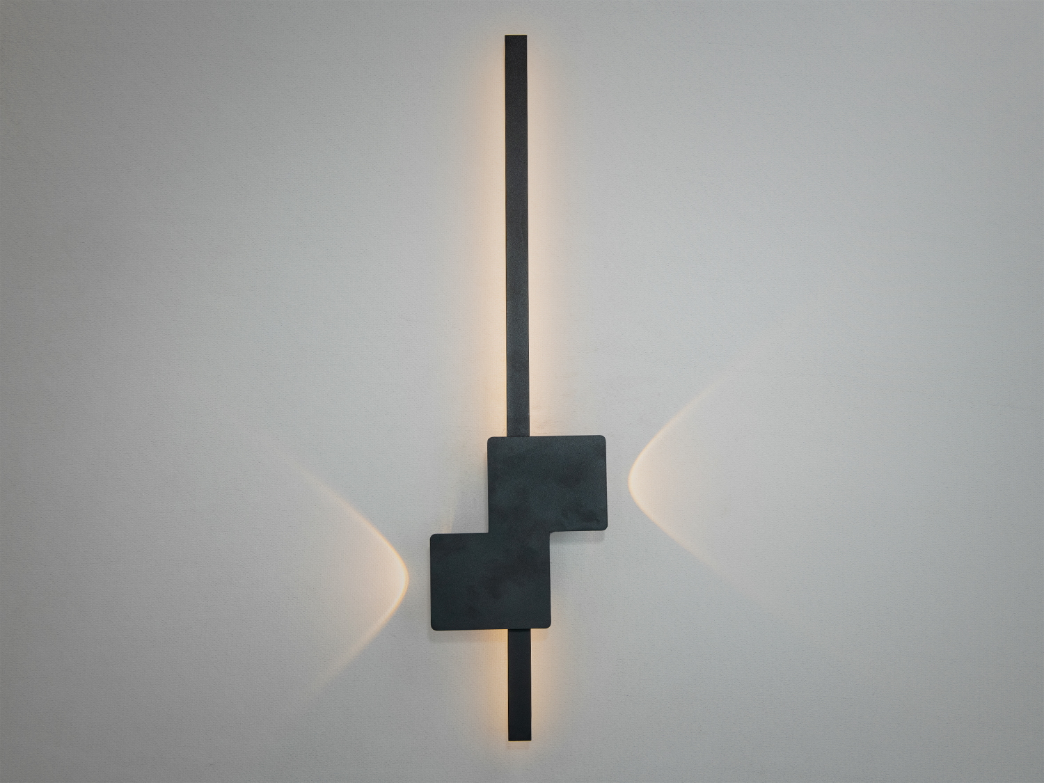 Стильний настінний світильник з чорного металу, що має вертикальну форму та квадратний акцент, ідеальний для мінімалістичного простору.