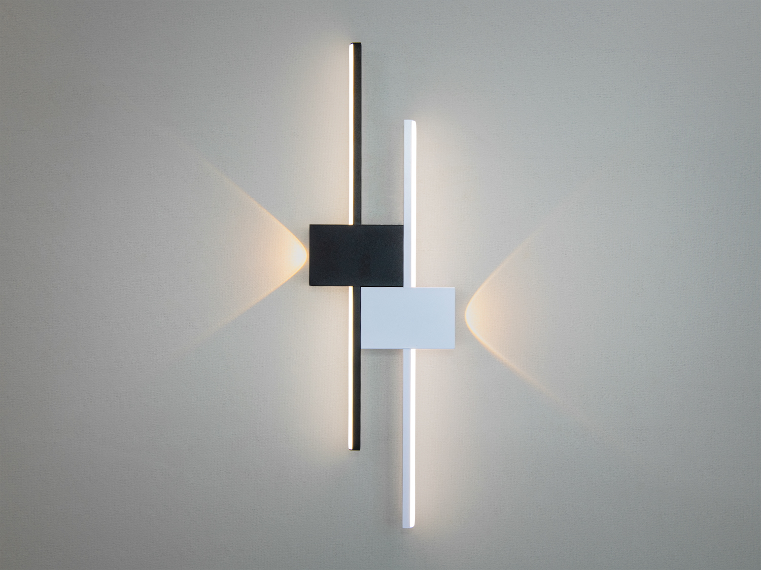 Геометричний настінний світильник з чорними та білими блоками, що створює м′яке освітлення. Підходить для вітальні.