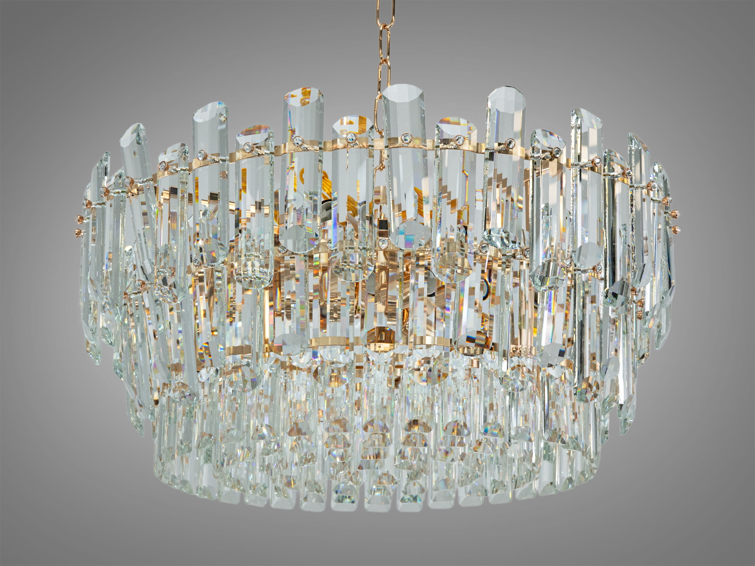 Кругла кришталева люстра з багаторівневими підвісками, що відбивають світло. Підходить для вітальні або їдальні.