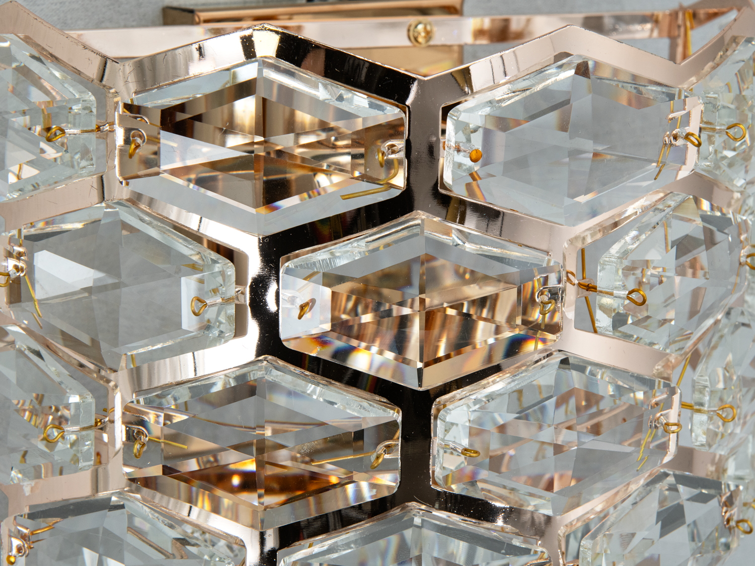 Детальний вигляд кришталевої структури світильника з шестикутними елементами. Металевий каркас має дзеркальну поверхню.