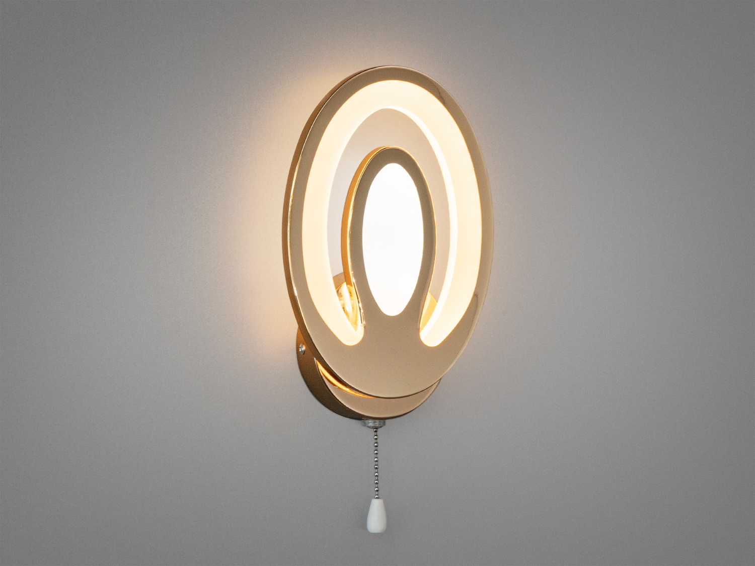Настінний LED світильник овальної форми з гладким золотистим покриттям. Включає підвісний вимикач для зручного монтажу.