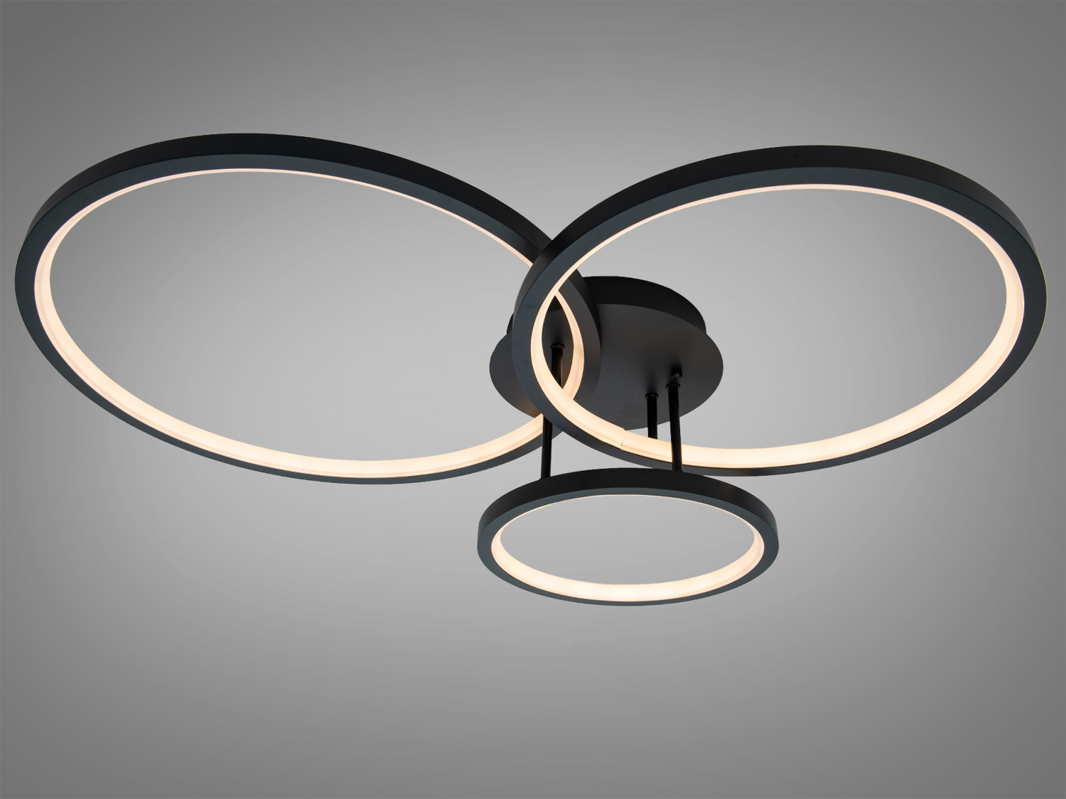 Чорна стельова люстра з трьома кільцями, що випромінює тепле світло, ідеально підходить для створення затишної атмосфери в кімнаті.
