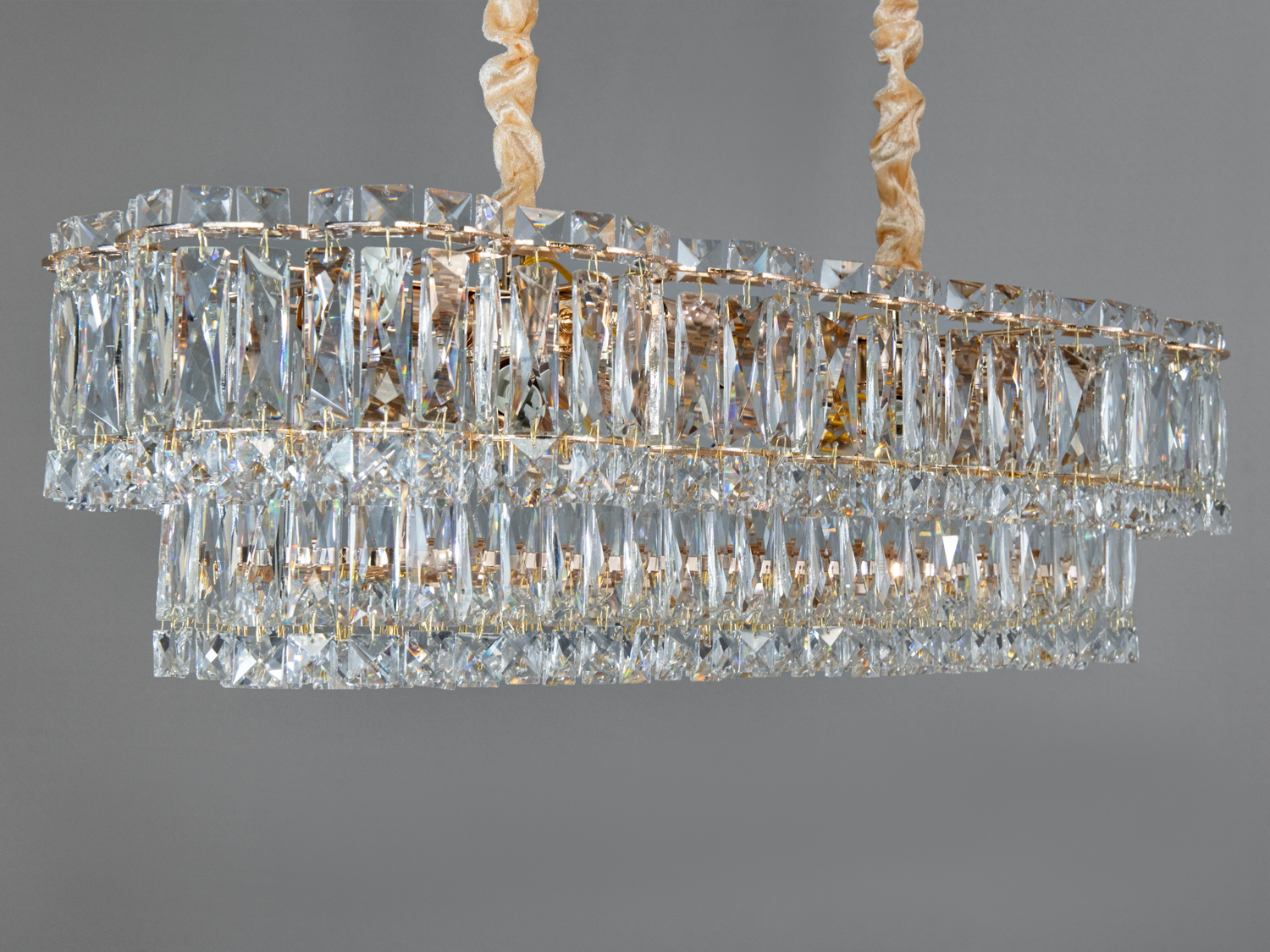 Елегантна люстра з кришталевими підвісками, закріплена на золотистій основі, створює розкішний вигляд у сучасному інтер′єрі.