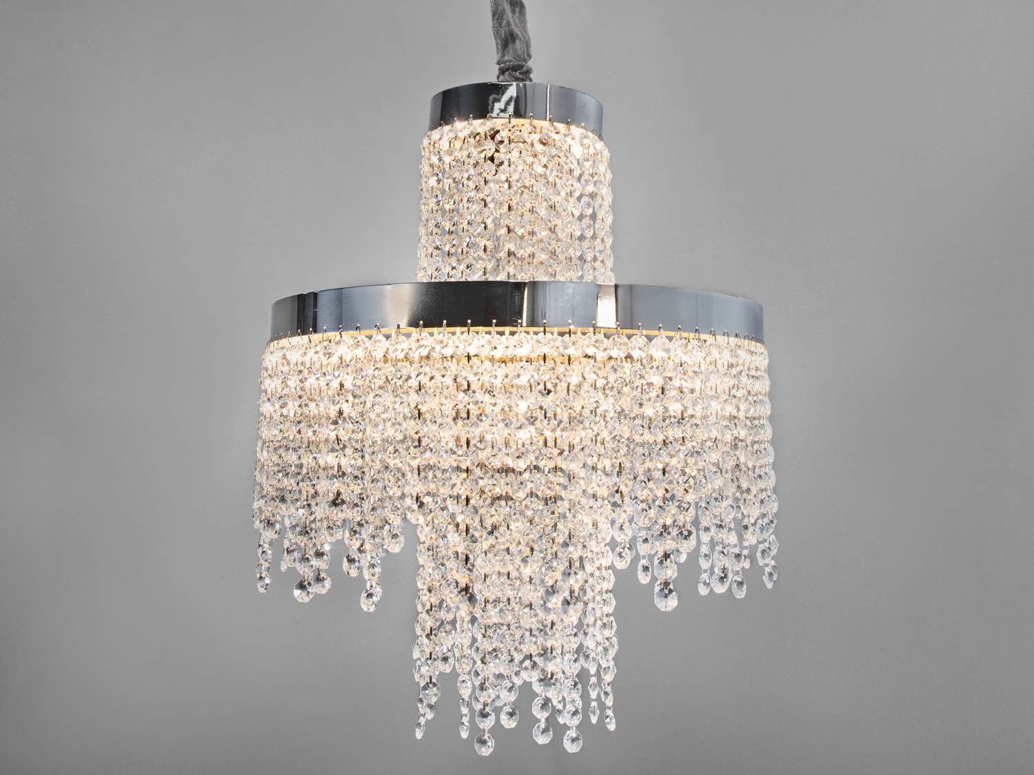 Блискуча люстра з двома рівнями кришталевих підвісок. Ідеальна для вітальні з високими стелями.