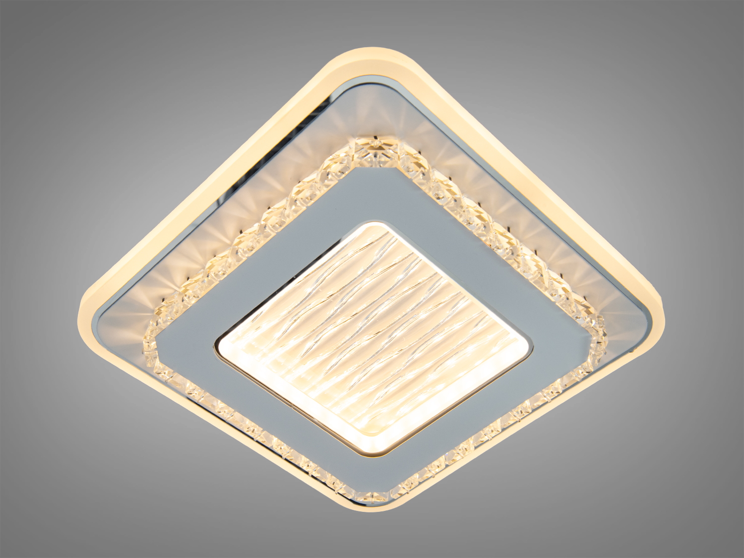 Діагонально встановлена квадратна лампа з прозорими краями. Випромінює тепле світло, що створює затишну атмосферу в кімнаті.