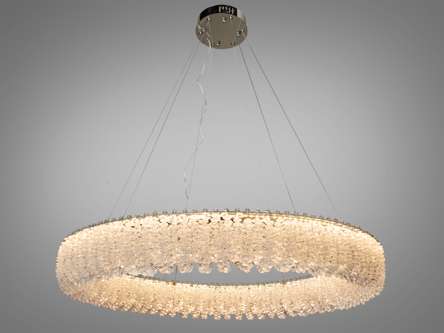 Овальна кришталева люстра з теплим світлом, підвішена на тонких дротах. Ідеальна для сучасного інтер′єру.