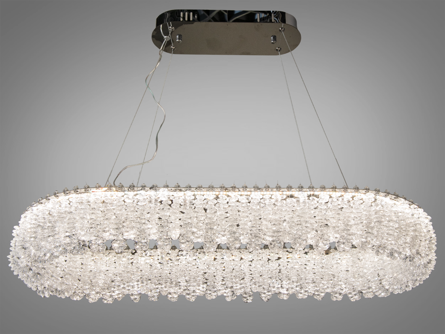 Овальна підвісна люстра з кришталевими підвісками, створює тепле освітлення, підходить для вітальні або їдальні.