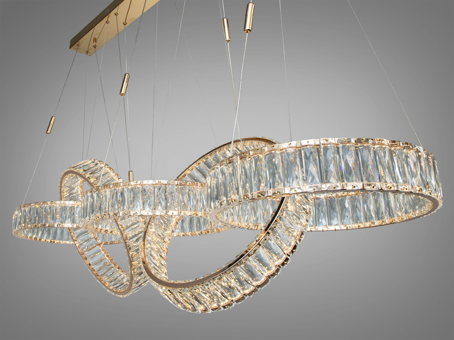 Люстра з прозорими кришталевими кільцями, підвішена на тонких тросах. Ідеально підходить для освітлення вітальні.