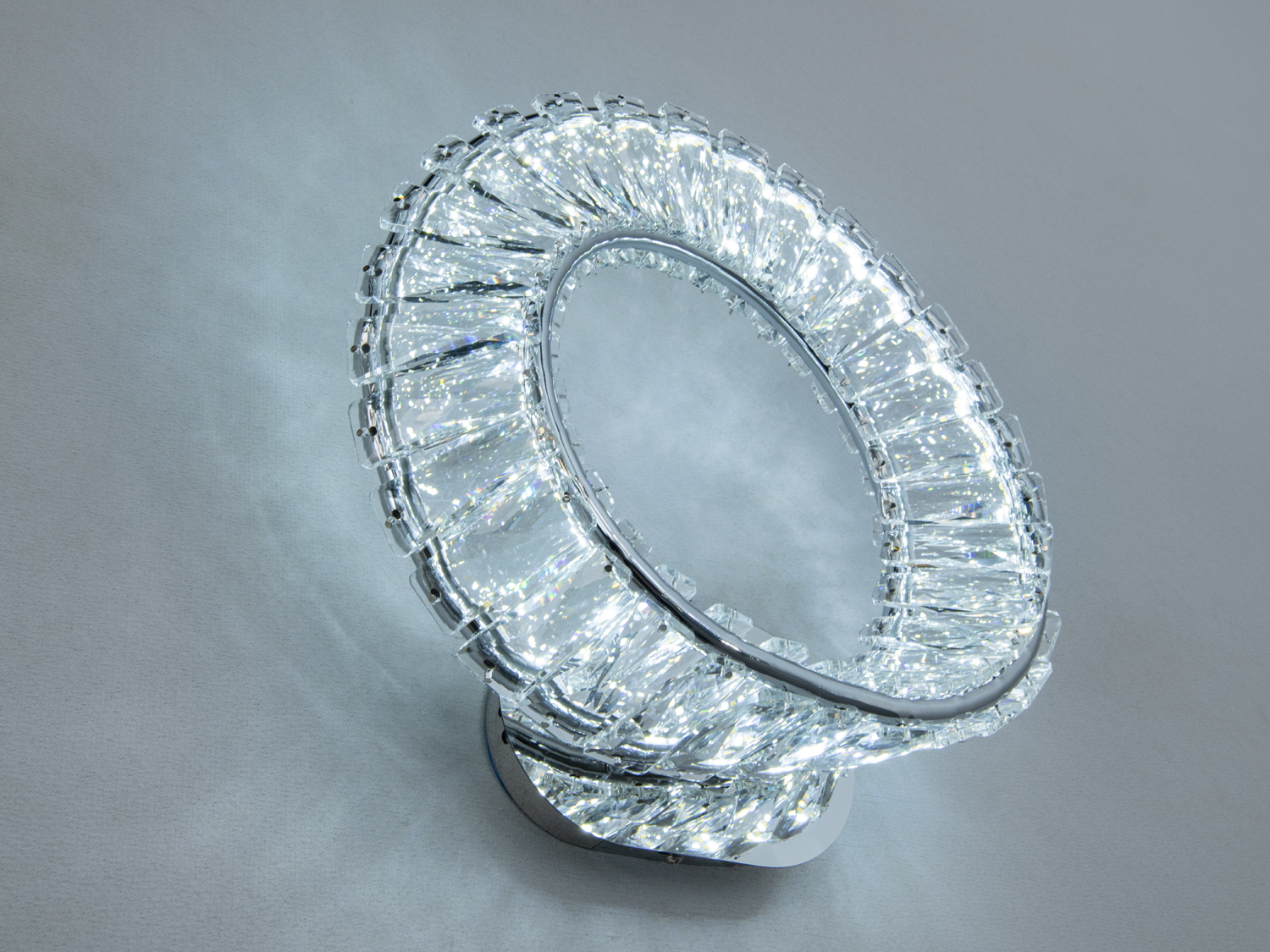 Світильник кільцевої форми з кришталевими деталями, що відбивають світло. Ідеальний для монтажу в вітальні.