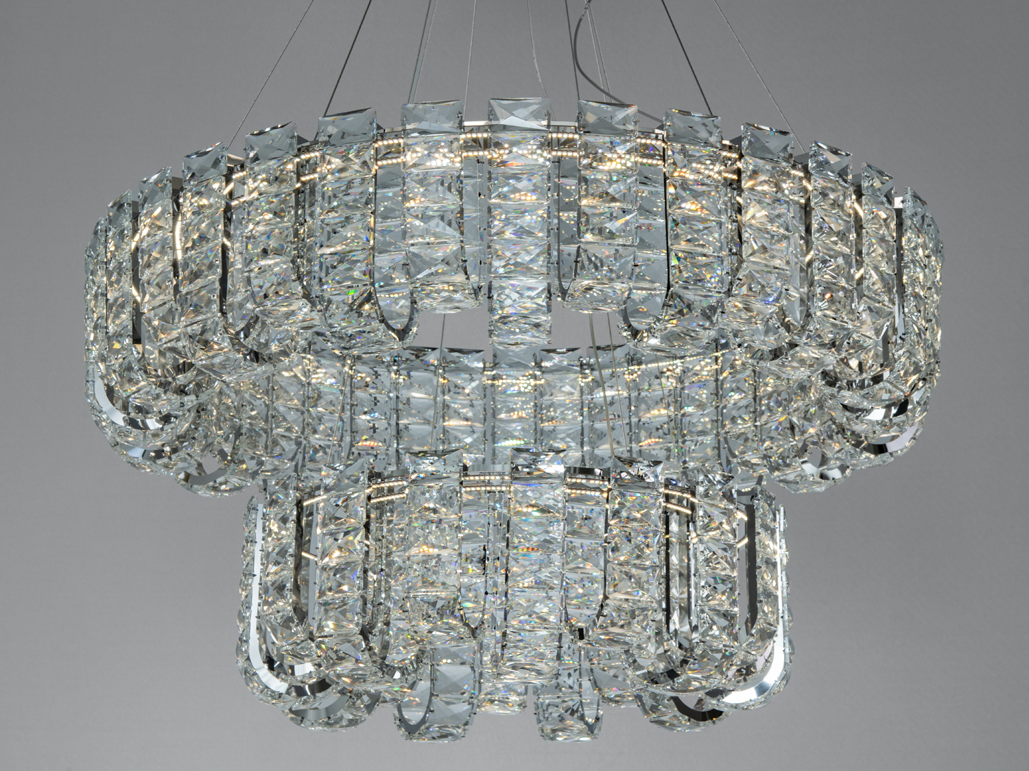Люстра з кришталевими підвісками, багаторівнева конструкція, підходить для просторих приміщень, забезпечує розкішне освітлення.