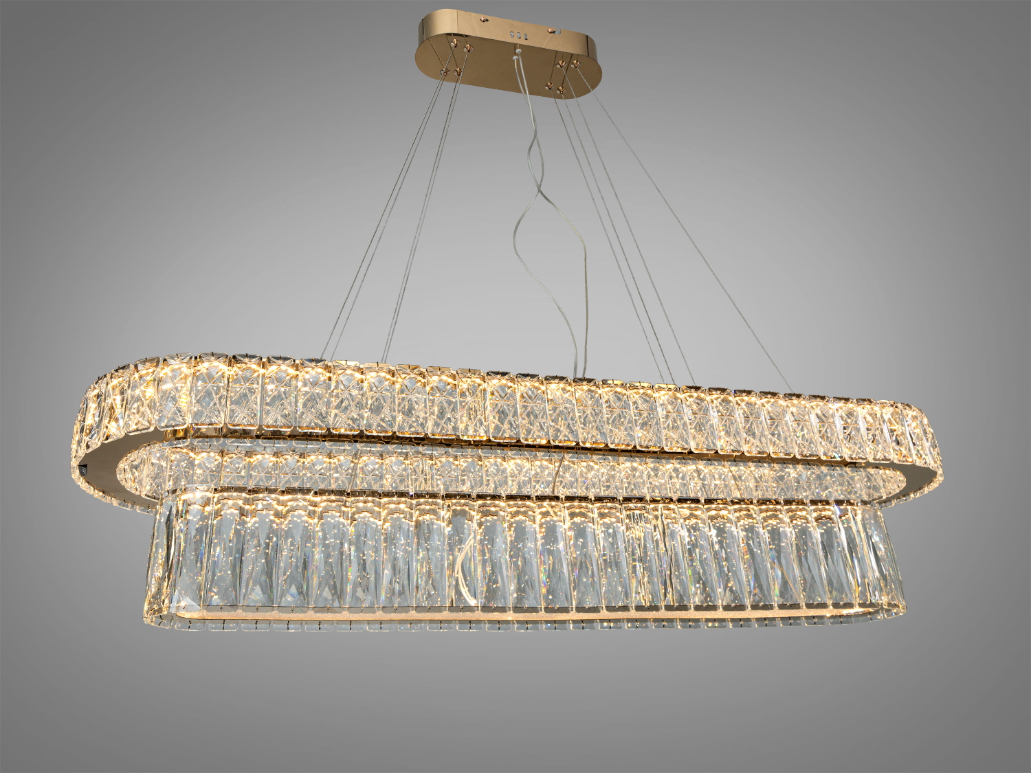 Люстра з двома рівнями кришталевих елементів, підвішена на тонких тросах, ідеальна для сучасних віталень.