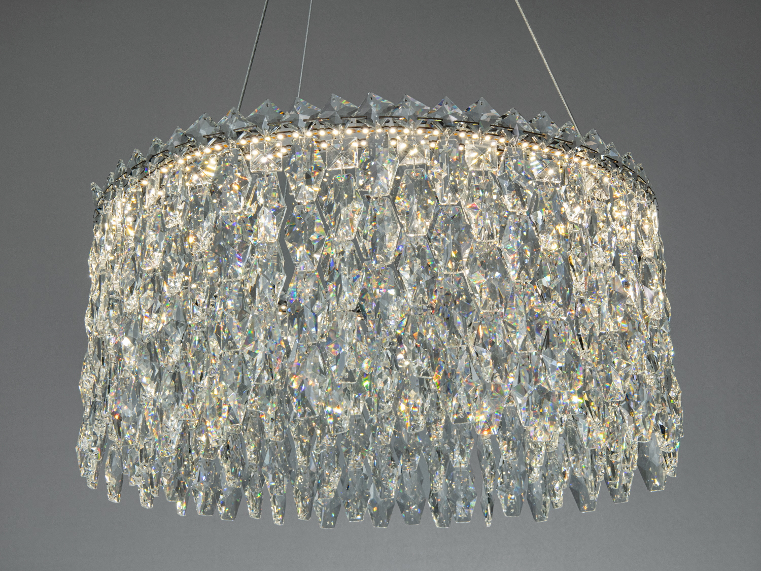 Близький вигляд кришталевої люстри з багатошаровими підвісками, що відбивають світло. Підходить для сучасного інтер′єру.