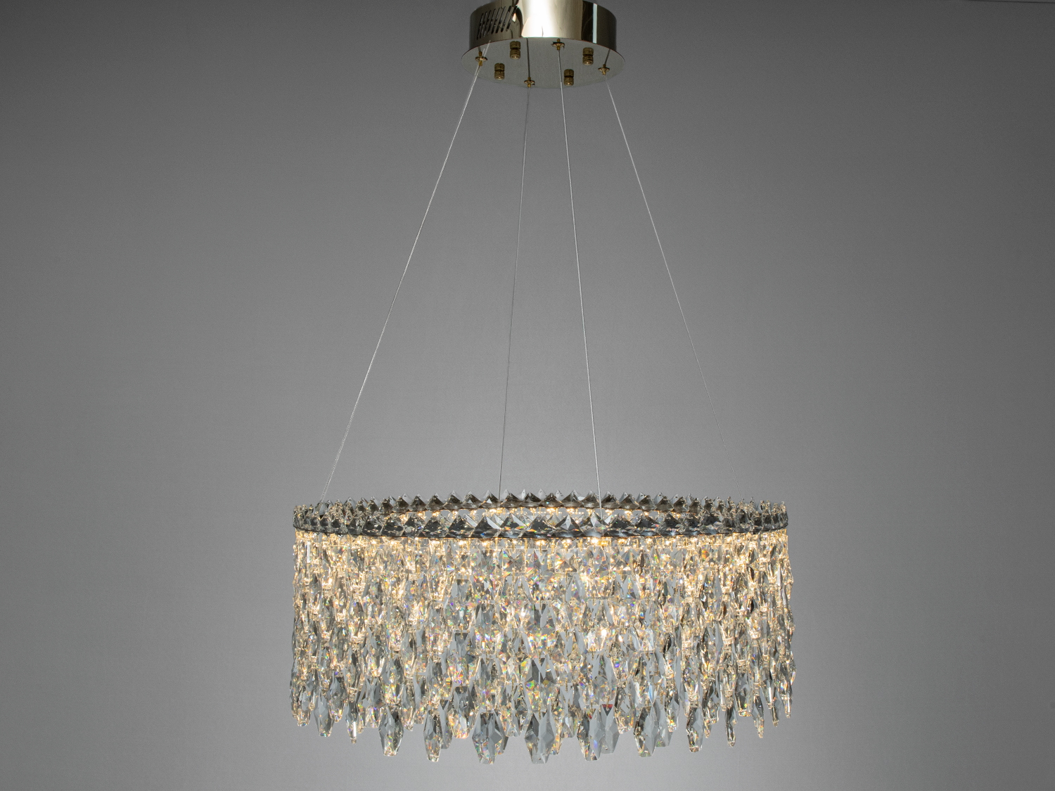 Кругла кришталева люстра з підвісами, підвішена на тонких тросах, ідеально підходить для сучасного інтер′єру.