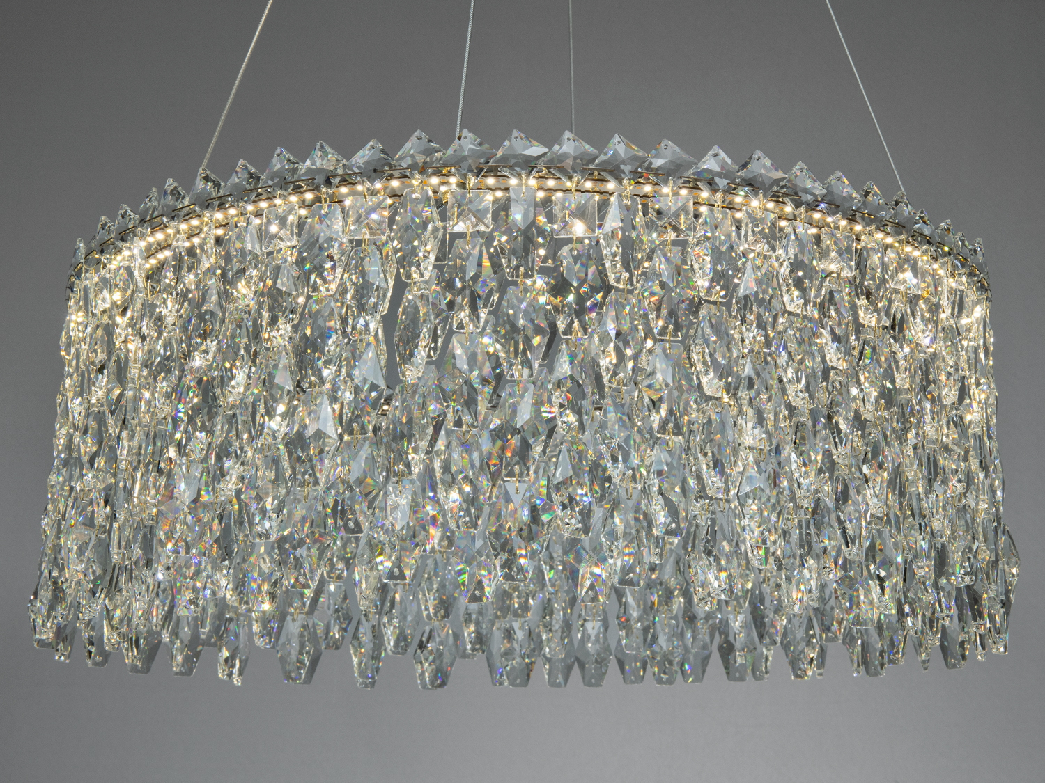 Кришталева люстра з багатошаровими підвісами, що створюють ефект блиску, підходить для вітальні чи їдальні.