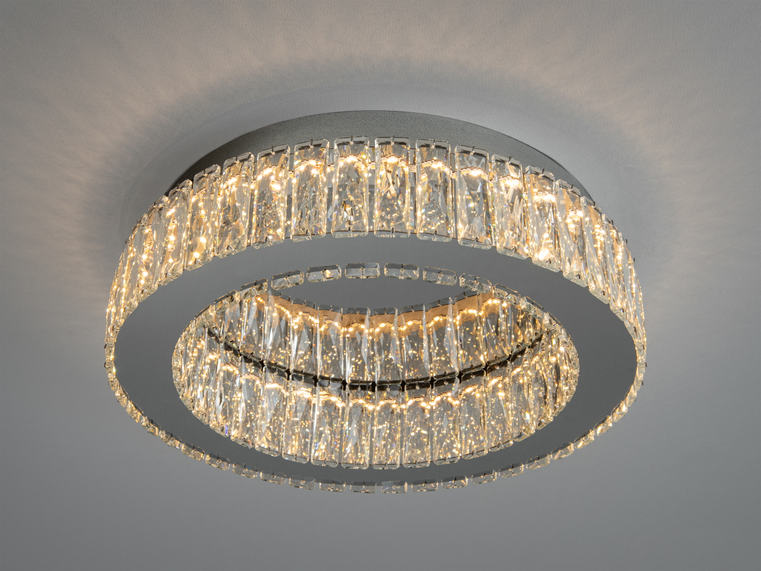 Стельова люстра з теплим жовтим світлом, виконана у вигляді двох концентричних кіл з кришталевих елементів. Ідеальна для затишного інтер′єру.