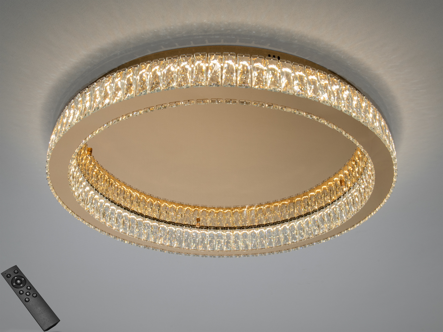 Кругла стельова люстра з кришталевими вставками, оснащена пультом дистанційного керування для регулювання яскравості світла.