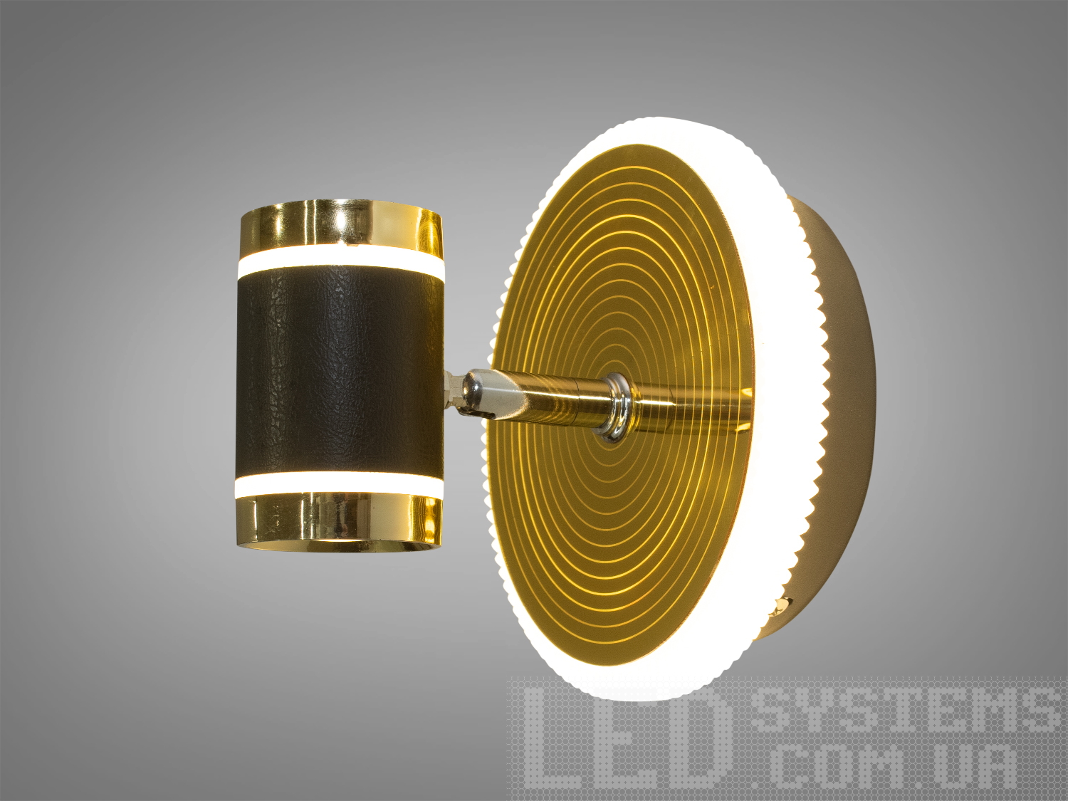 Настінний світильник з круглою основою, оздобленою золотистими кільцями, та циліндричним абажуром з чорної шкіри, підходить для сучасного інтер′єру.