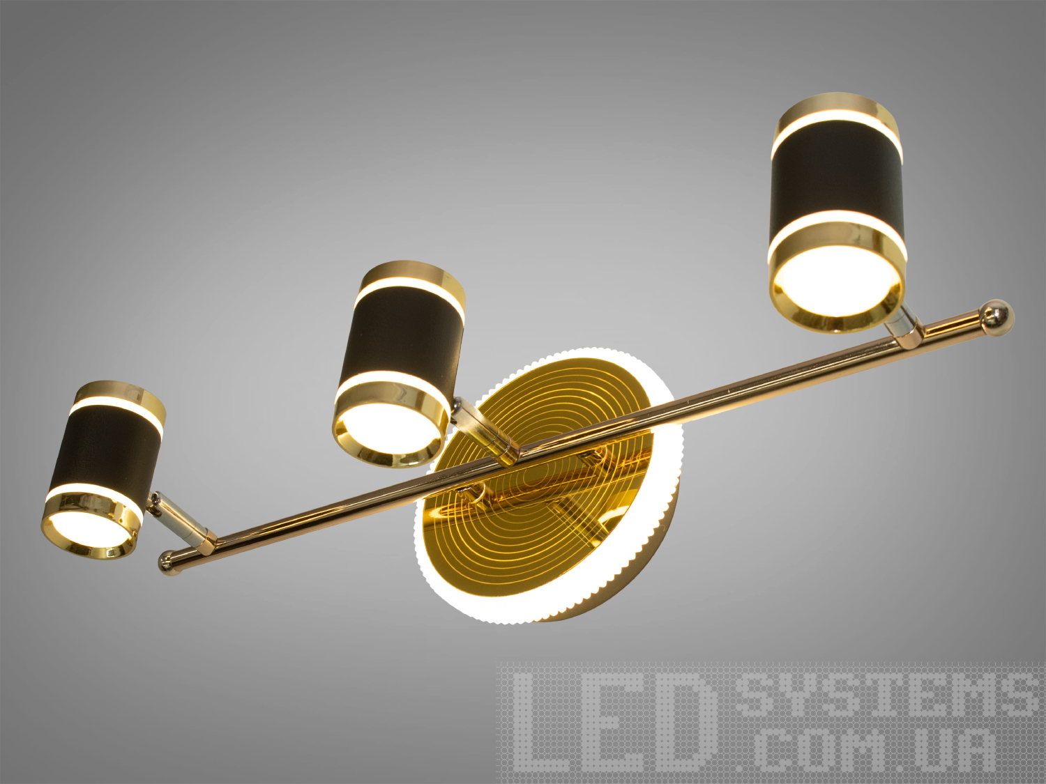 Триламповий світильник з циліндричними плафонами, чорний корпус, золотисті елементи, підходить для офісного простору.