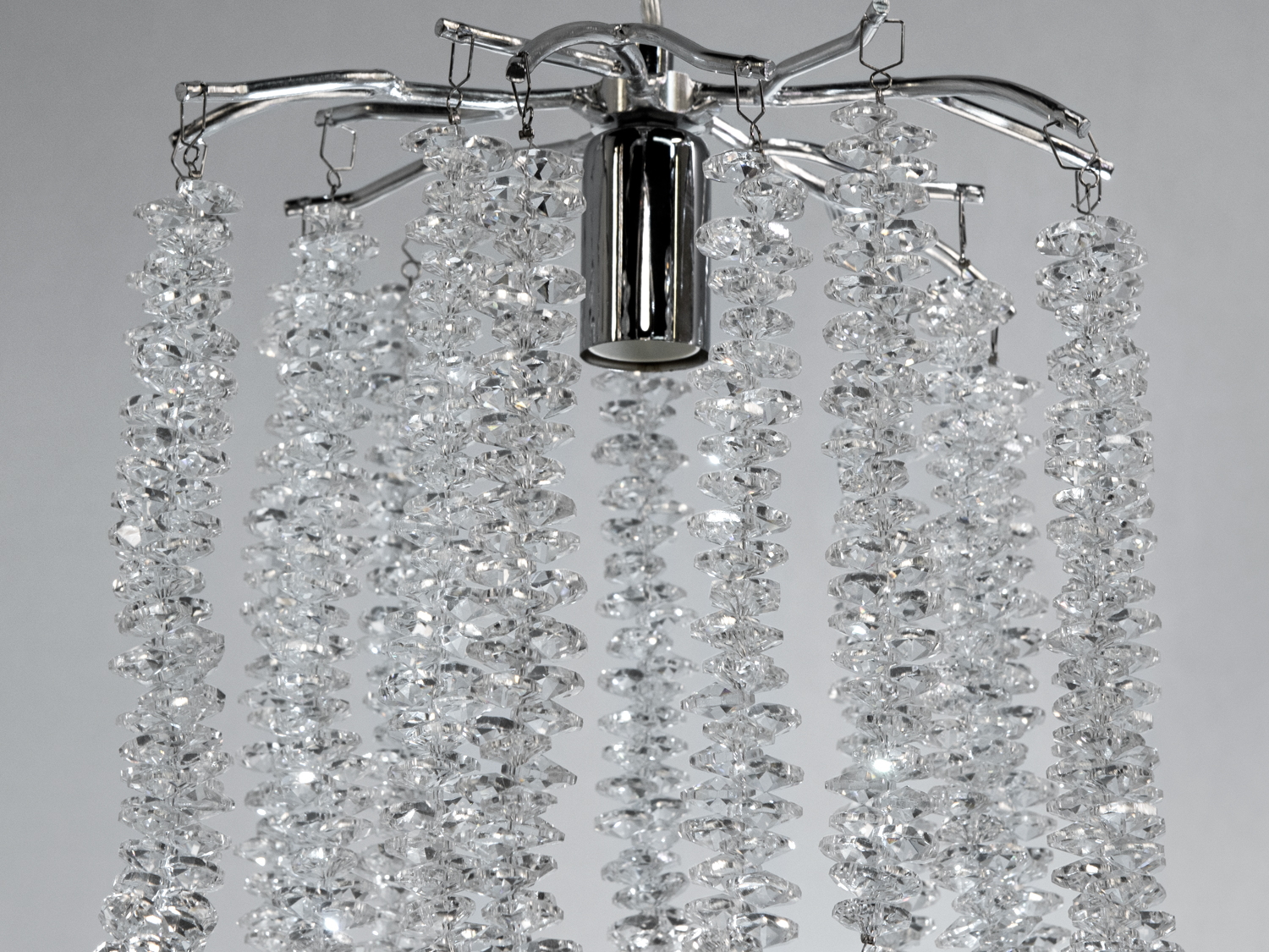 Детальний вигляд кришталевих підвісок світильника, що відображають світло та створюють мерехтливий ефект.