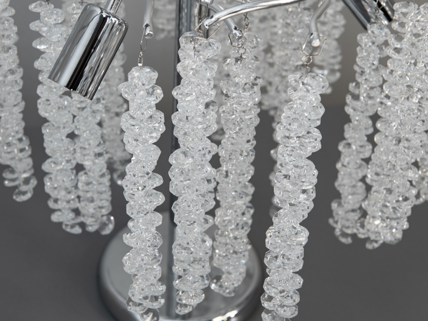 Детальний вигляд кришталевих підвісок настільної лампи. Прозорі елементи створюють ефект розсіювання світла, підходить для декору.