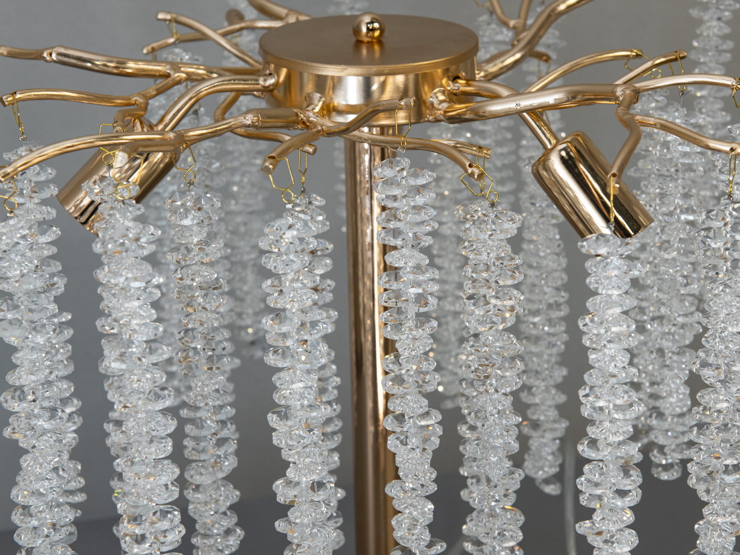 Детальний вигляд кришталевих підвісок настільної лампи на золотистій основі. Підвіски створюють ефект розкішного освітлення в кімнаті.