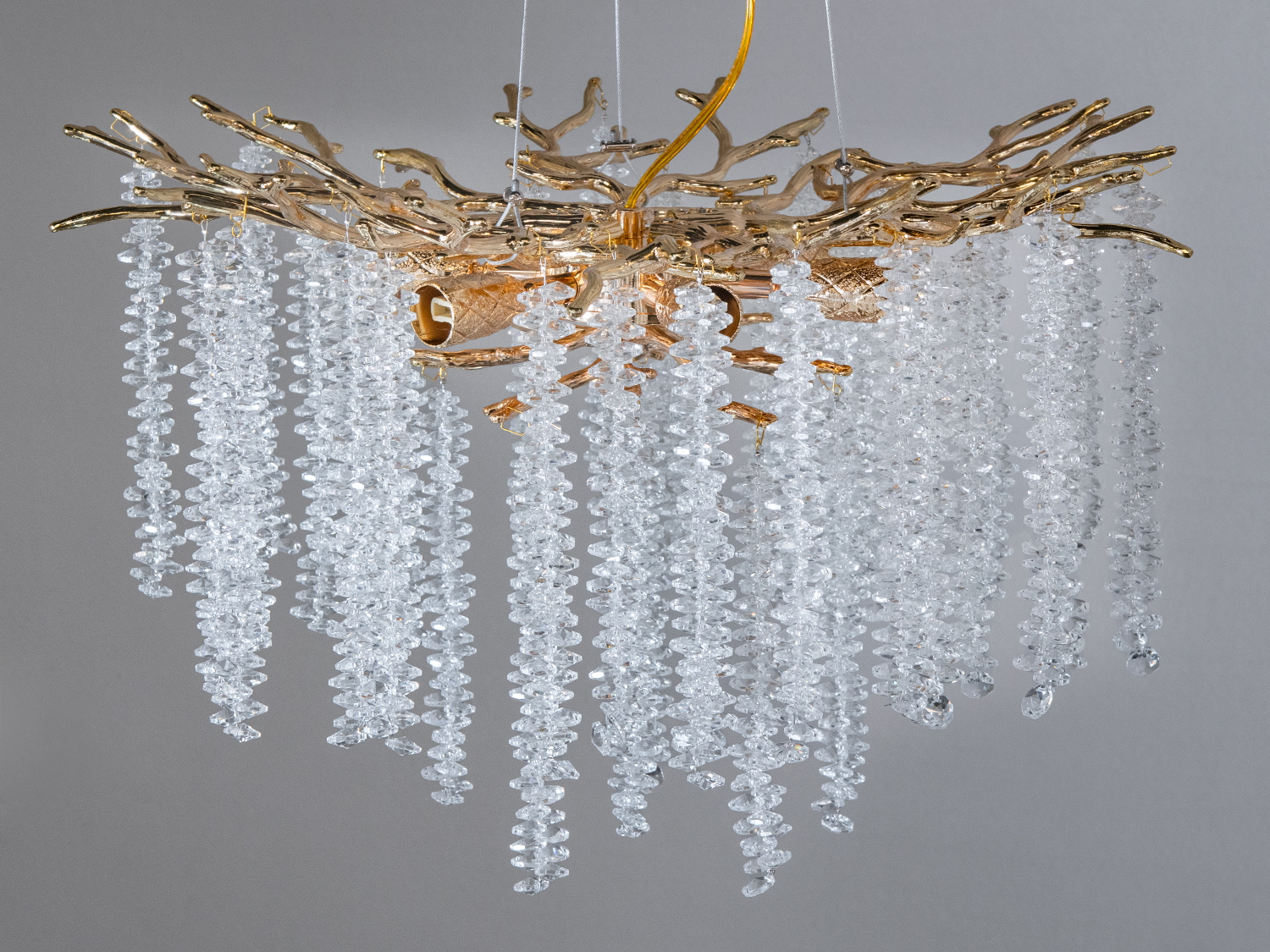 Люстра з гіллястим каркасом та кришталевими підвісками, що імітують краплі води, підходить для розкішного освітлення вітальні.