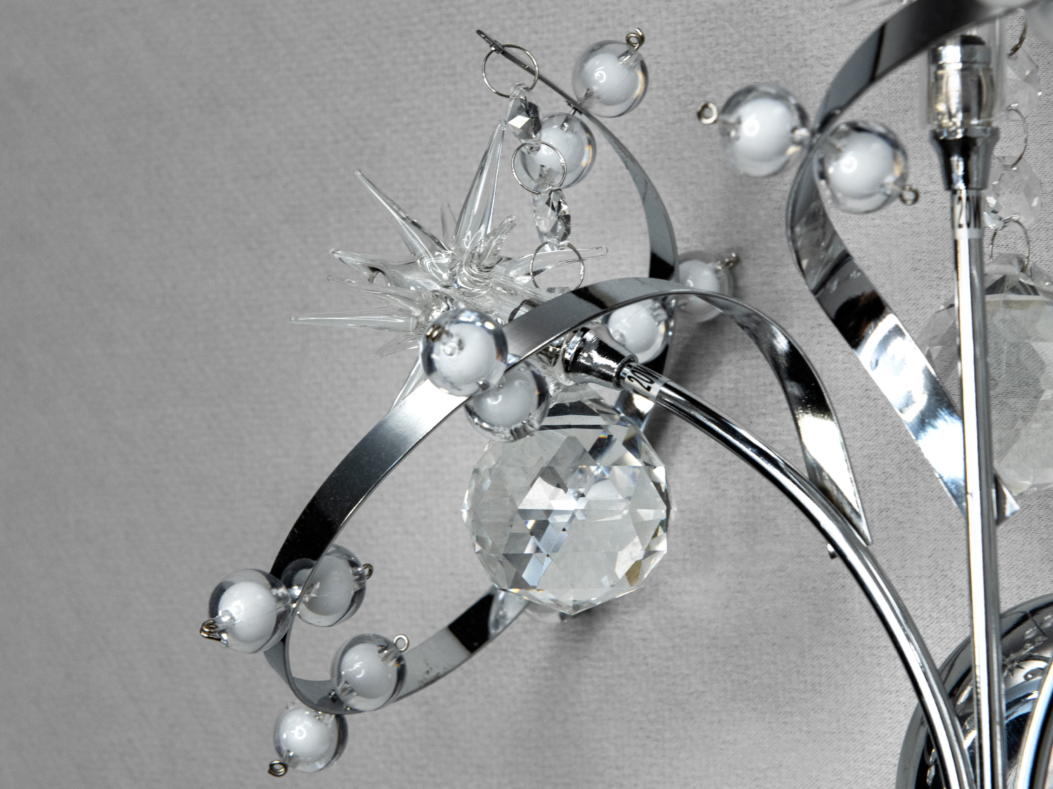 Близький план світильника з кришталевими підвісками та металевими дугами. Підходить для освітлення вітальні.