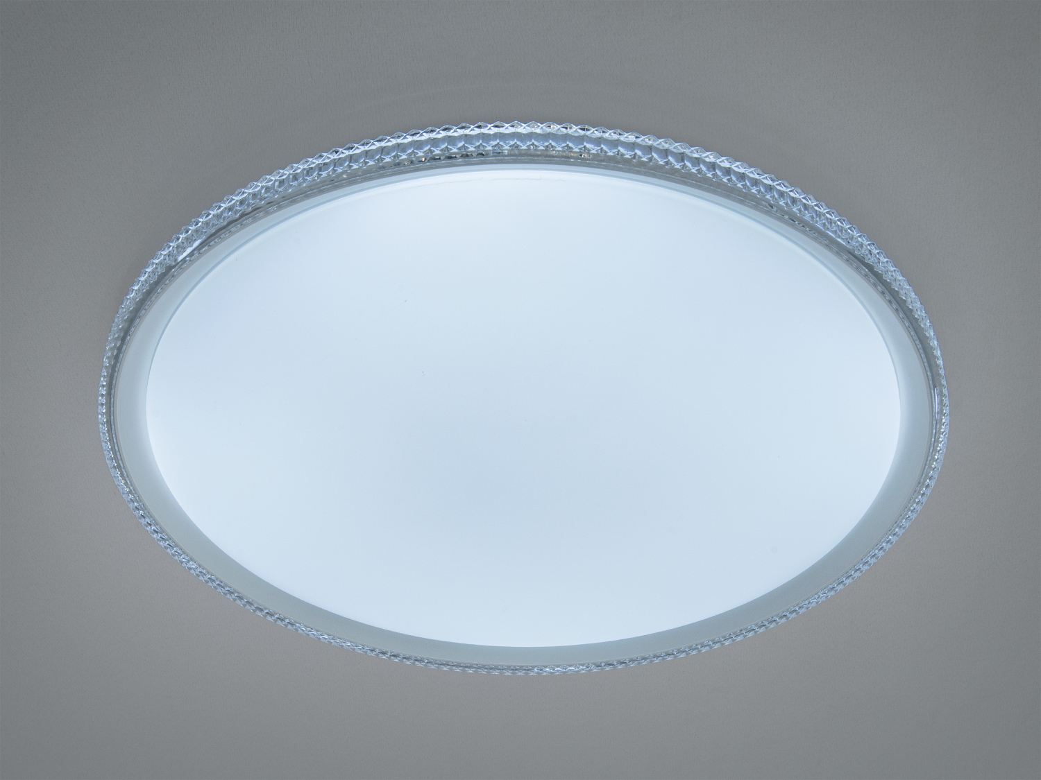 Кругла стельова лампа з прозорим обідком, що створює м′яке розсіяне світло. Підходить для сучасних інтер′єрів.