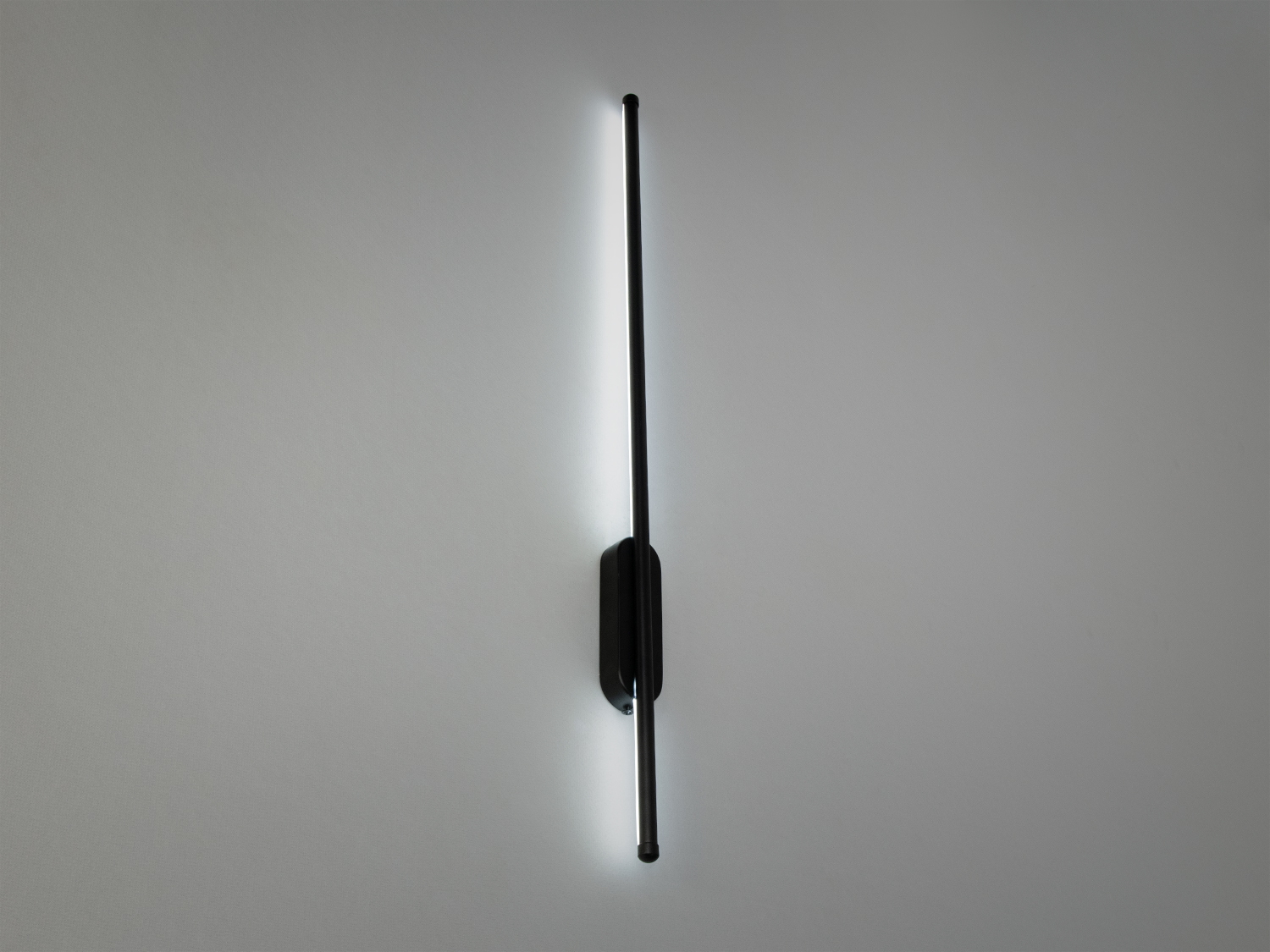 Настінний світильник з чорним корпусом, що створює акцентне освітлення. Підходить для мінімалістичного дизайну.