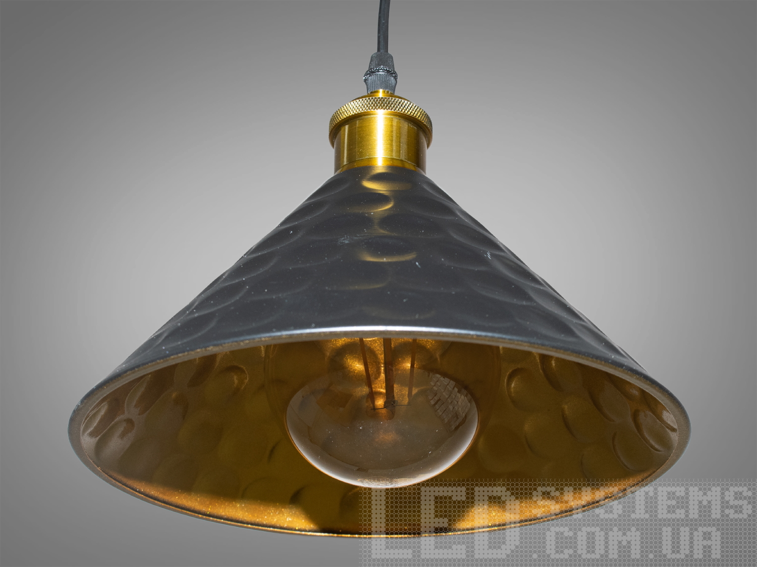 Світильник-підвіс в стилі лофт, який ідеально підходить під лампочку Едісона, об'єднує  у собі вишуканість  та  індустріальний шарм. Його дизайн підкреслює автентичність та теплоту лампочки Едісона, створюючи унікальний елемент декору та освітлення.Характеристики світильника:Лампа Едісона як центральний елемент: Спеціально розроблений дизайн, що виділяє та підкреслює лампу Едісона як центральний елемент світильника. Застосування лампи Едісона з декоративними нитками або нестандартною формою додає виробу вишуканості та тепла. Лампочка Едісона надає приємне приглушене світло, створюючи тепло та затишну атмосферу в місці розташування світильника.Матеріали з індустріальним виглядом: Використовуються металеві або чорні матеріали, що надають індустріальний шарм та вишуканість. Мінімалізм цього світильника підкреслить вашу індивідуальність і відчуття стилю. Металеві елементи можуть мати сліди старіння, підряпини чи інші недоліки, що є характерними для стилю лофт та надають світильнику виразний вигляд.Лофтовий дизайн: З підвісом у вигляді ланцюга чи троса, грубими металевими деталями та відкритим дизайном, що додає стиль лофту. Стиль «Лофт» зараз дуже популярний, його люблять як творчі особистості, так і вельми практичні люди, які віддають перевагу комфорту і простоті в інтер'єрі. Світильники в стилі «лофт» ідеально впишуться в сучасні будинки, квартири, кафе, арт-простори, коворкінги, квеструми.Підвісний світильник ідеально поєднується з іншими індустріальними деталями, такими як відкриті труби, цегла або металеві стільниці.Можливість регулювання висоти: Дозволяє легко адаптувати світильник до різних просторових умов.Сфери використання:Ресторани та кафе: Створює тепло та затишне освітлення, ідеально підходить для створення атмосфери в зонах обіду або бару.Житлові приміщення: Виглядає чудово у вітальнях, кухнях чи спальнях, додаючи індустріальний акцент до інтер'єру.Магазини та виставкові зони: Створює стильний вигляд для приміщень, де важливий дизайн та видиму привабливість. Вигідно підкреслює стильні товари або предмети мистецтва, надаючи їм індивідуальний вигляд.Фото- та відеостудії: Забезпечує освітлення з характером для створення унікальних фото чи відеоматеріалів.Цей світильник-підвіс у стилі лофт з лампочкою Едісона створює особливу атмосферу, де тепло та стиль індустріального дизайну взаємодіють, надаючи приміщенню унікальний і вишуканий вигляд.Лампа в комплект не входить.