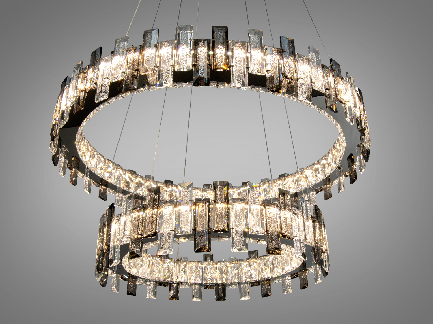 Люстра з двома кільцями, що випромінюють тепле світло, підвішена на тонких тросах. Ідеальна для віталень.