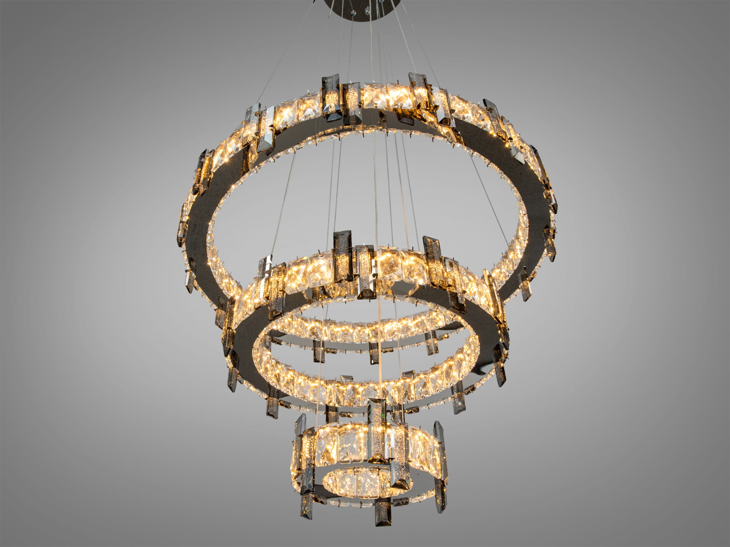 Три кільця люстри з теплим світлом, кришталеві елементи створюють затишну атмосферу.