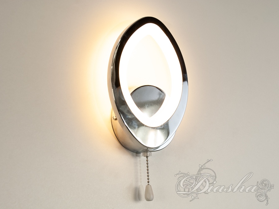 Настінний світильник з теплим світлом, овальної форми, має металевий корпус і шнур для увімкнення. Підходить для затишних приміщень.