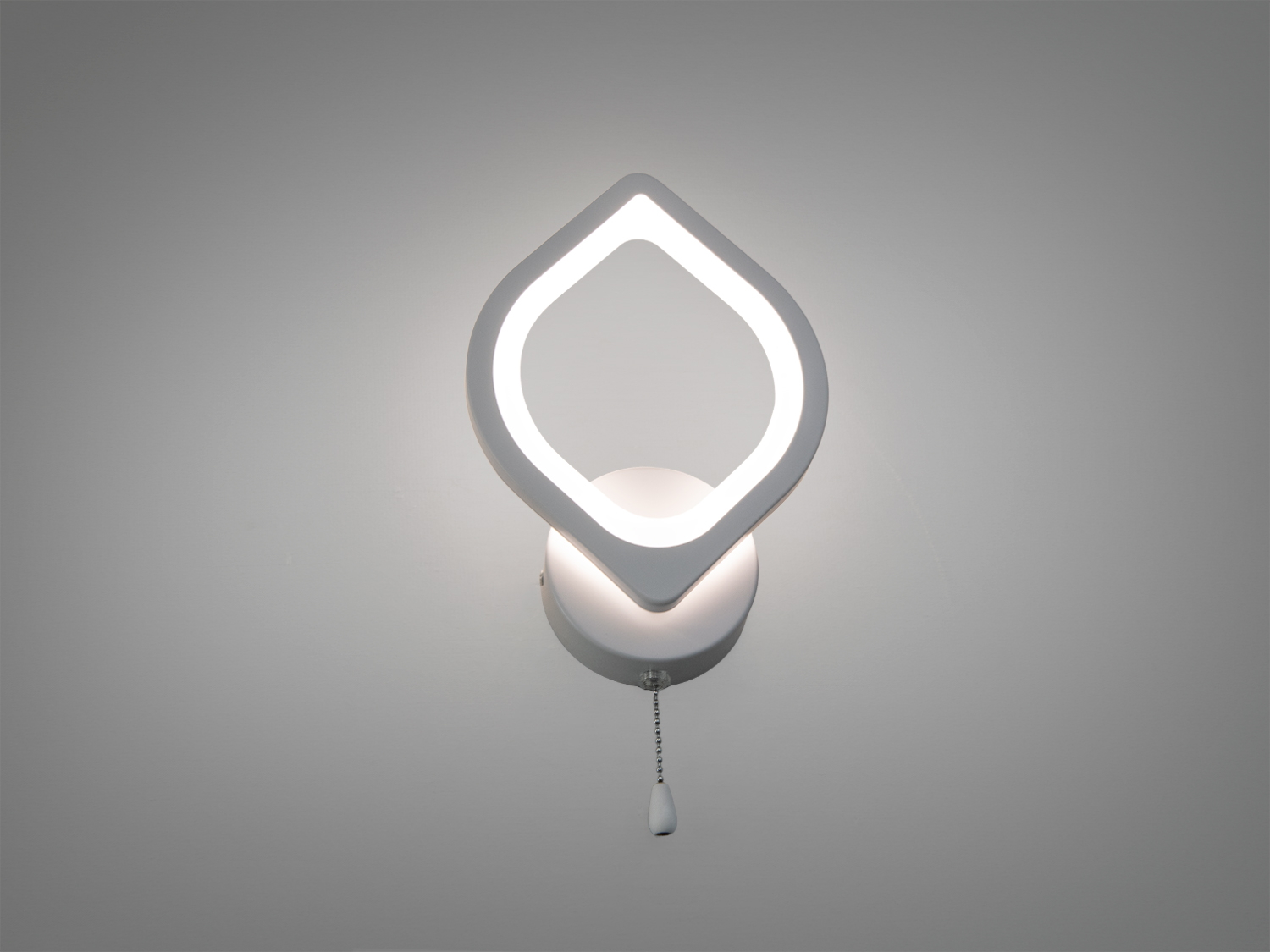 Білий настінний світильник з плафоном у вигляді краплі або листочка, має зручний ланцюжковий вимикач. Підходить для мінімалістичного інтер′єру.