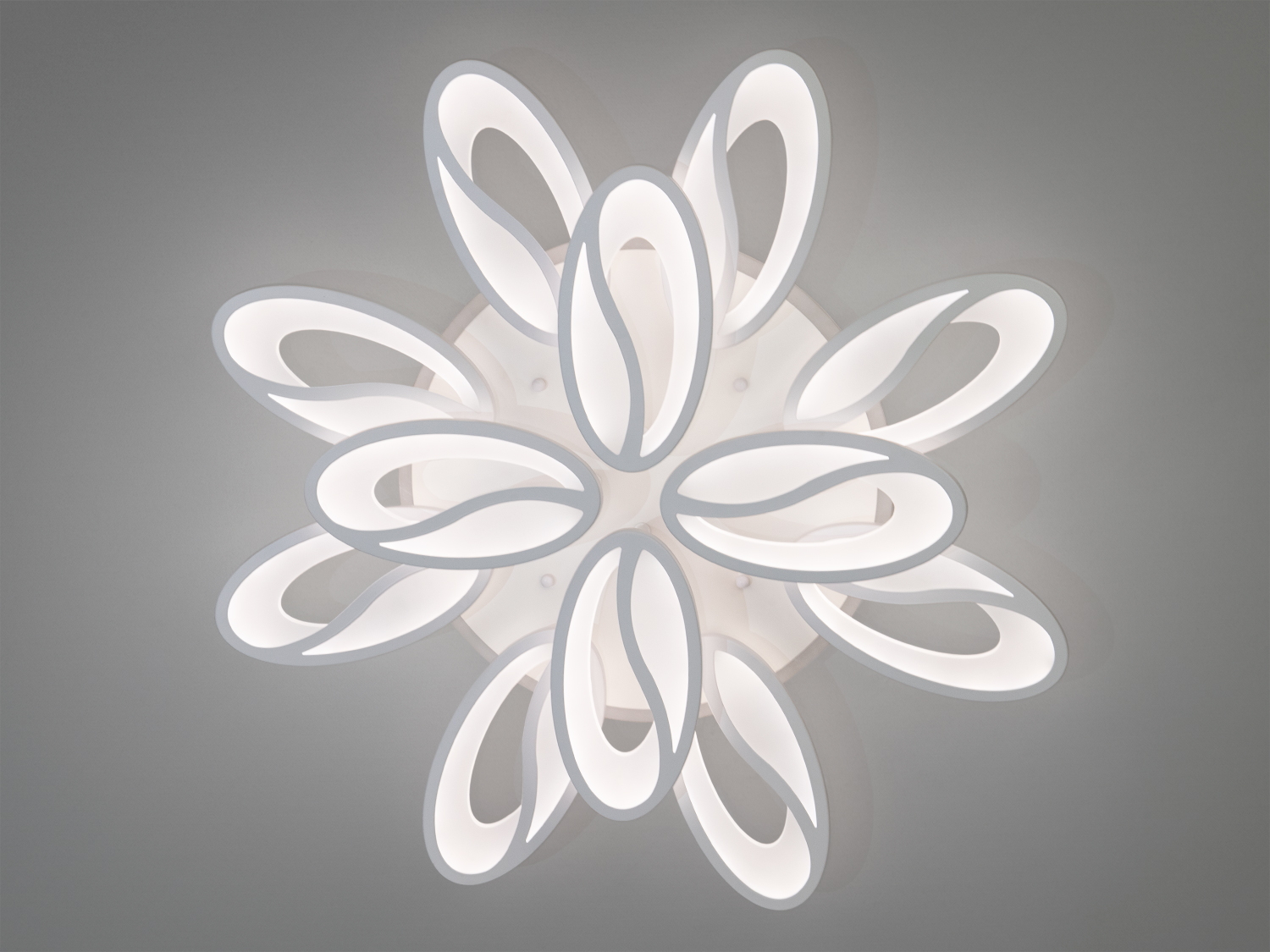 Біла стельова люстра з овальними елементами, що нагадують квітку. Випромінює нейтральне світло, підходить для офісу або кабінету.