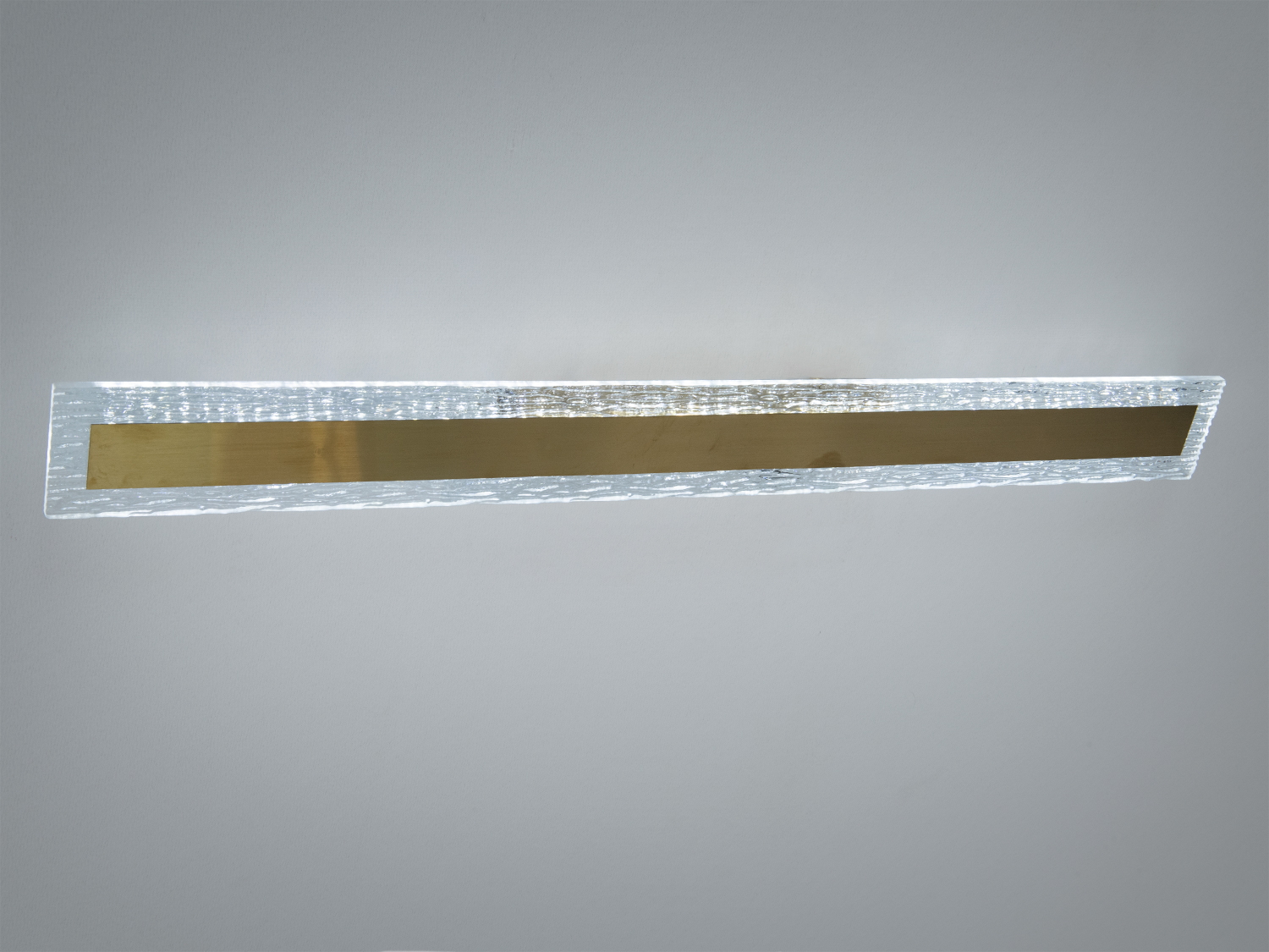 Світильник для стіни з металевим корпусом, має витягнуту форму та золотисту вставку, ідеальний для мінімалістичного дизайну.