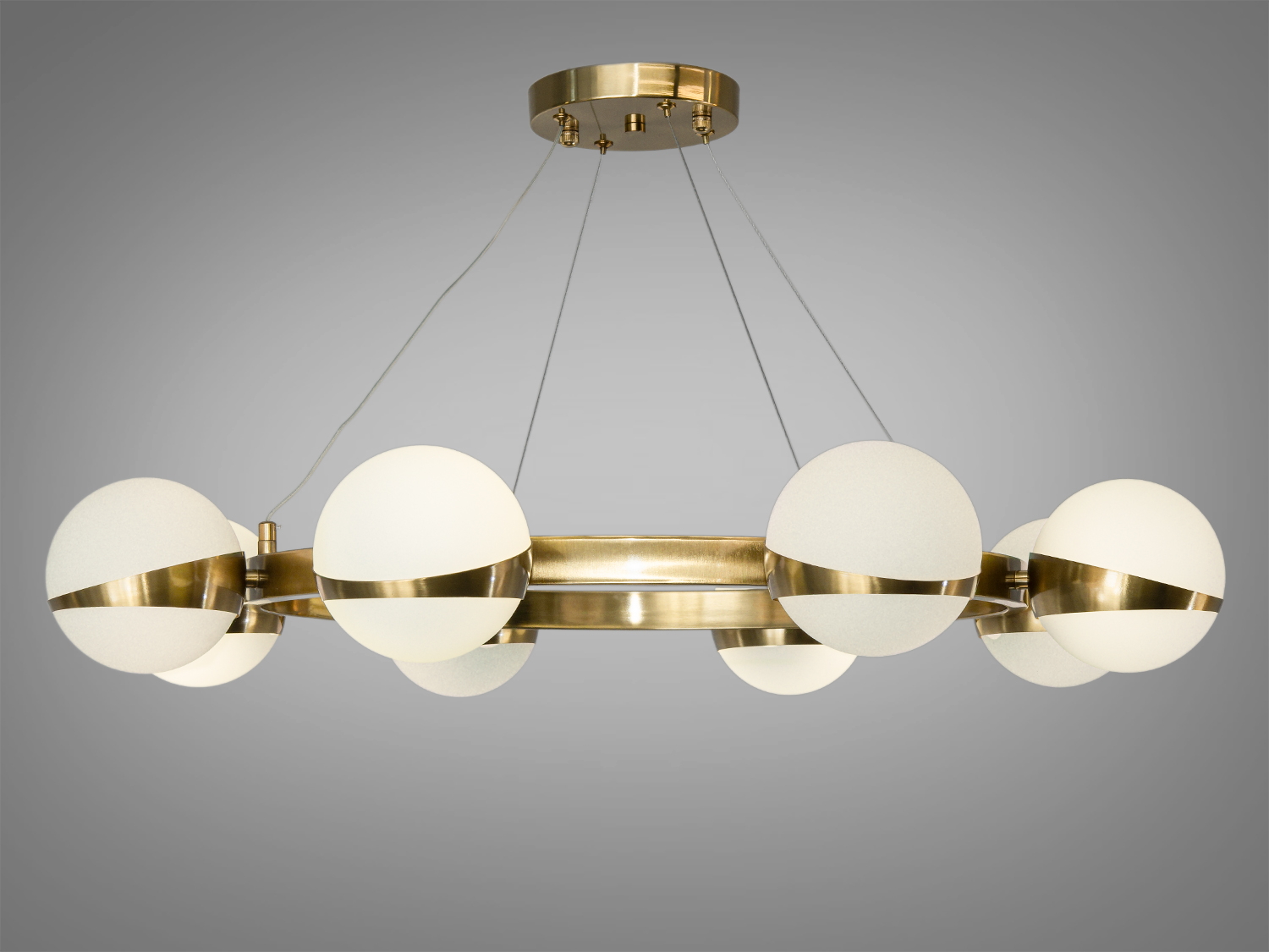 Металеве кільце люстри в кольорі бронзи, яке висить на напівпрозорих підвісах, створює враження легкості та елегантності. 