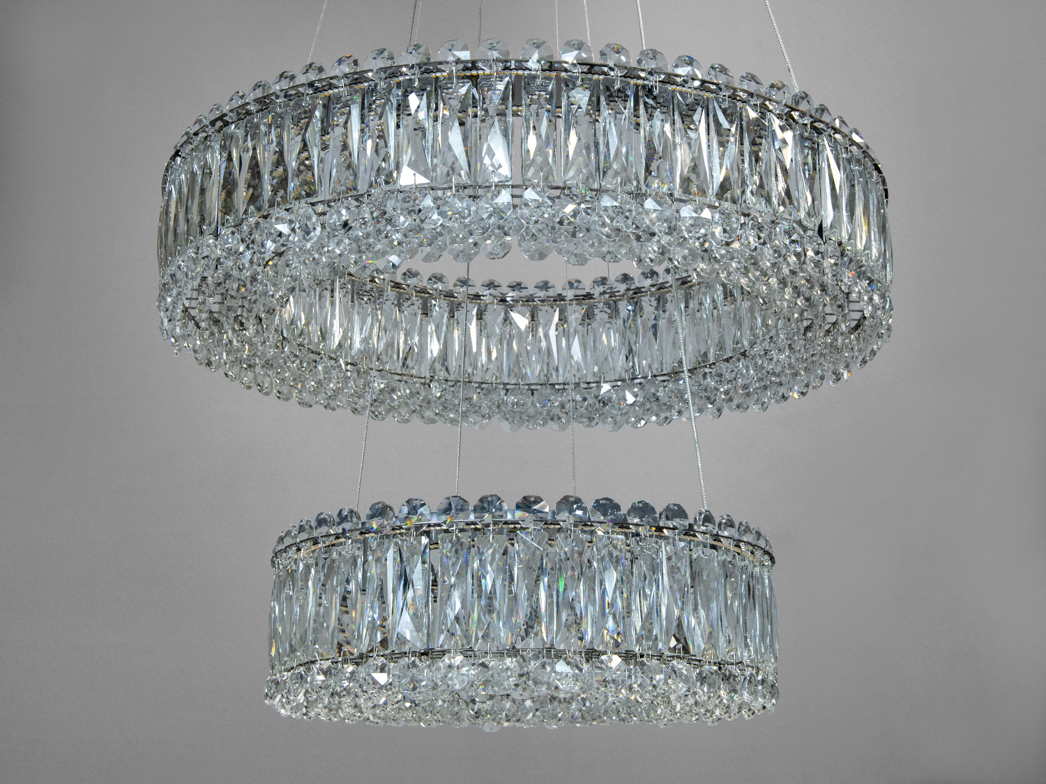 Підвісна люстра з двома кільцями, прикрашена прозорими кристалами. Відмінно підходить для вітальні або холу.