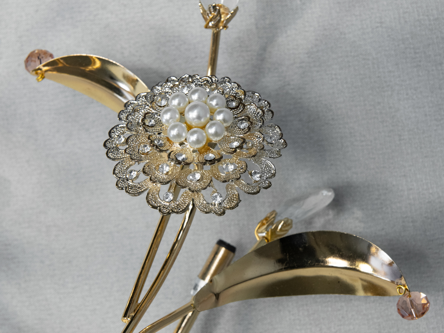 Деталь кришталевої квітки настінного світильника з перлинами та золотистими елементами. Ідеально підходить для розкішного декору.