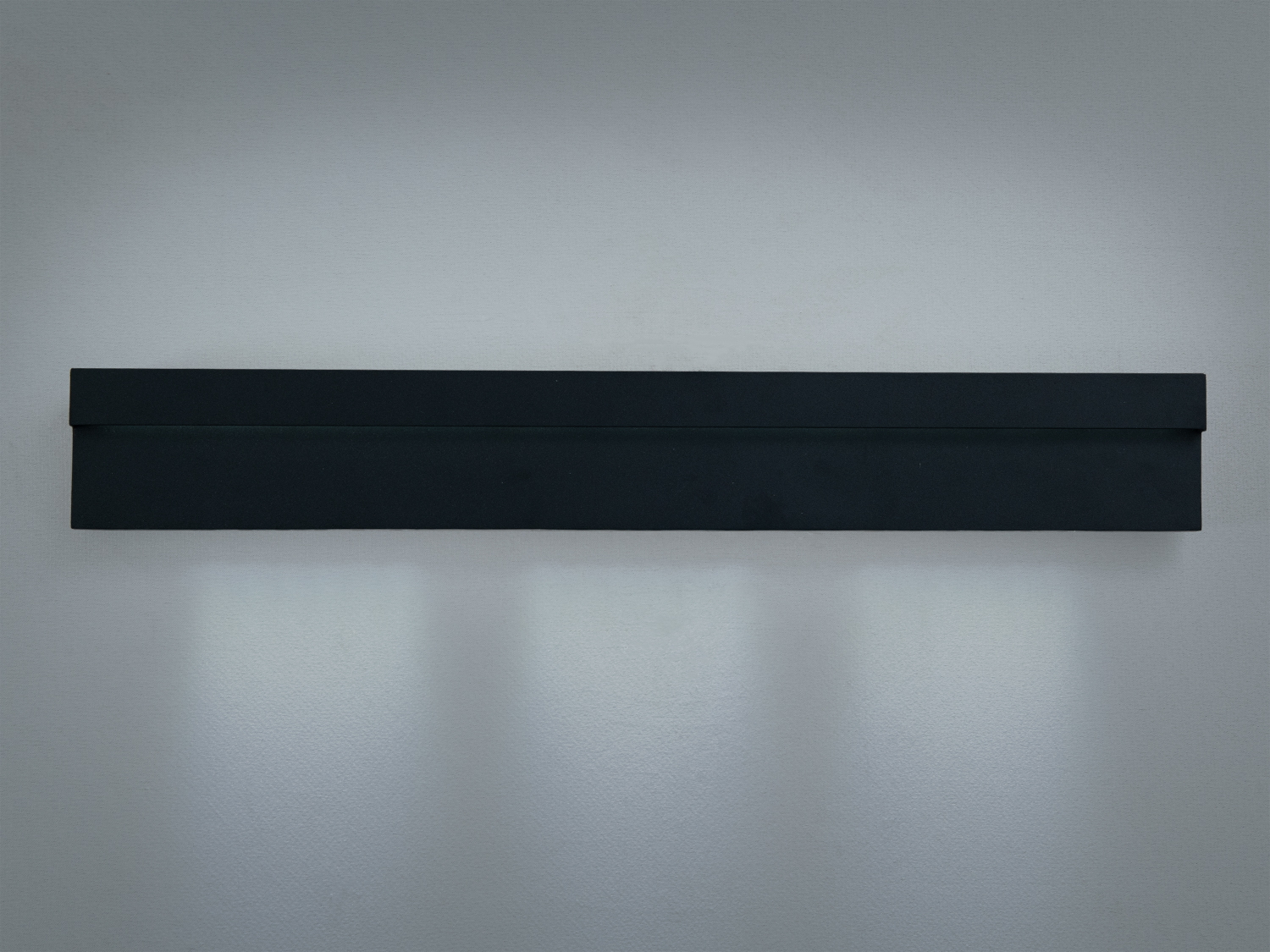 Чорний настінний світильник з мінімалістичним дизайном. Випромінює світло вниз, підходить для освітлення коридорів.