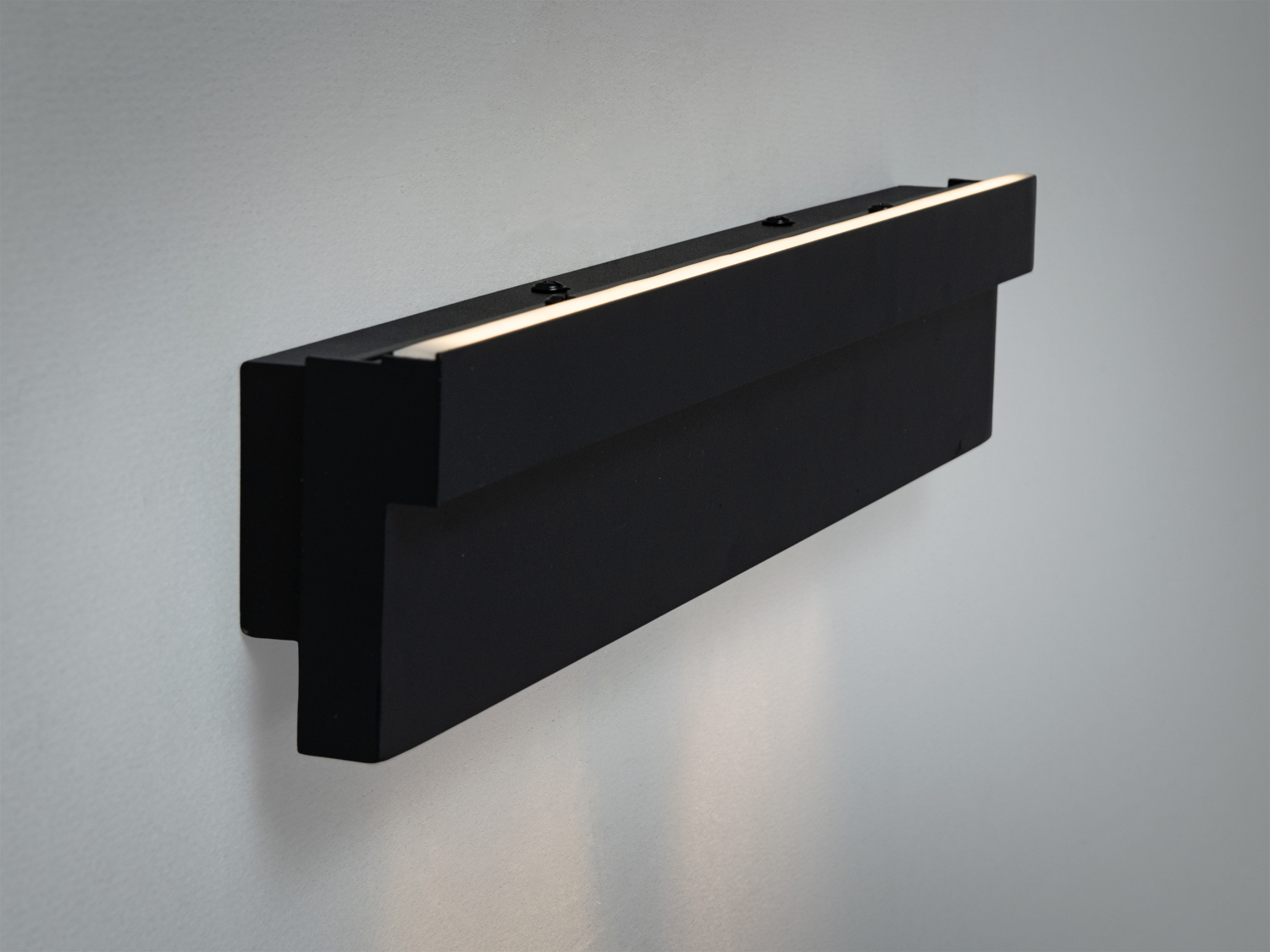 Чорний настінний світильник з акцентом на мінімалістичний дизайн. Має приховане кріплення, що забезпечує чистий вигляд.