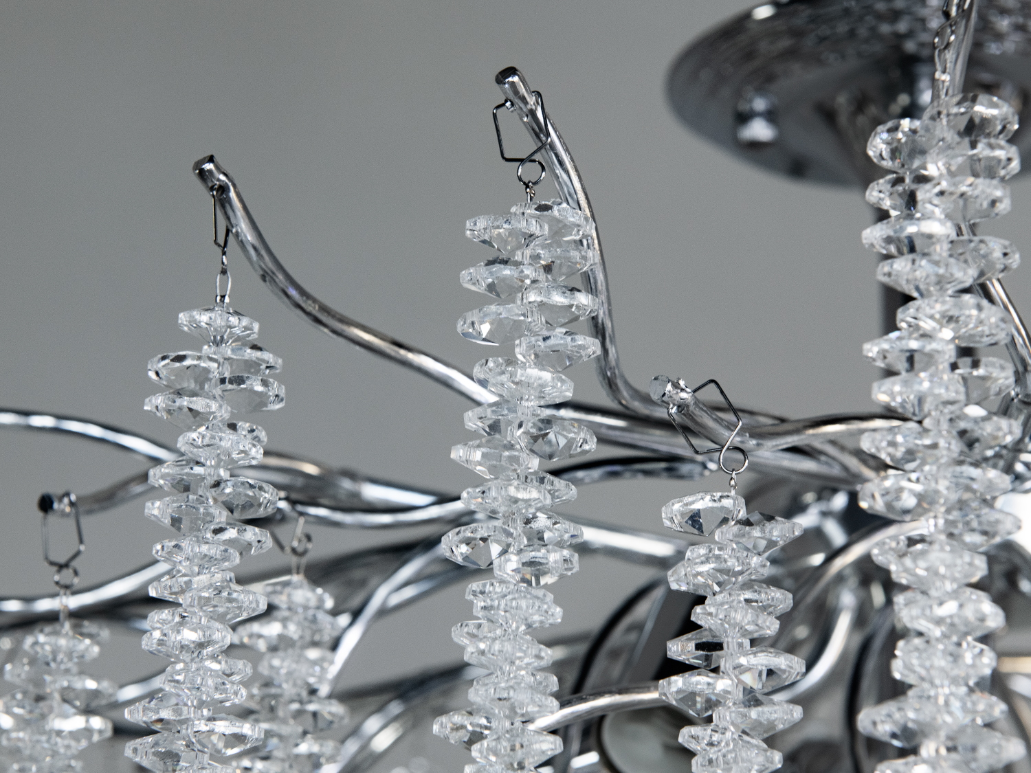 Детальне зображення кришталевих підвісок на металевій основі. Підвіски мають форму гранованих крапель, що підсилюють блиск.