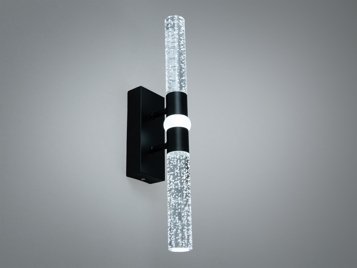 Вертикальний настінний світильник з акриловими трубками, заповненими бульбашками, створює ефектний акцент. Чорний корпус додає елегантності.