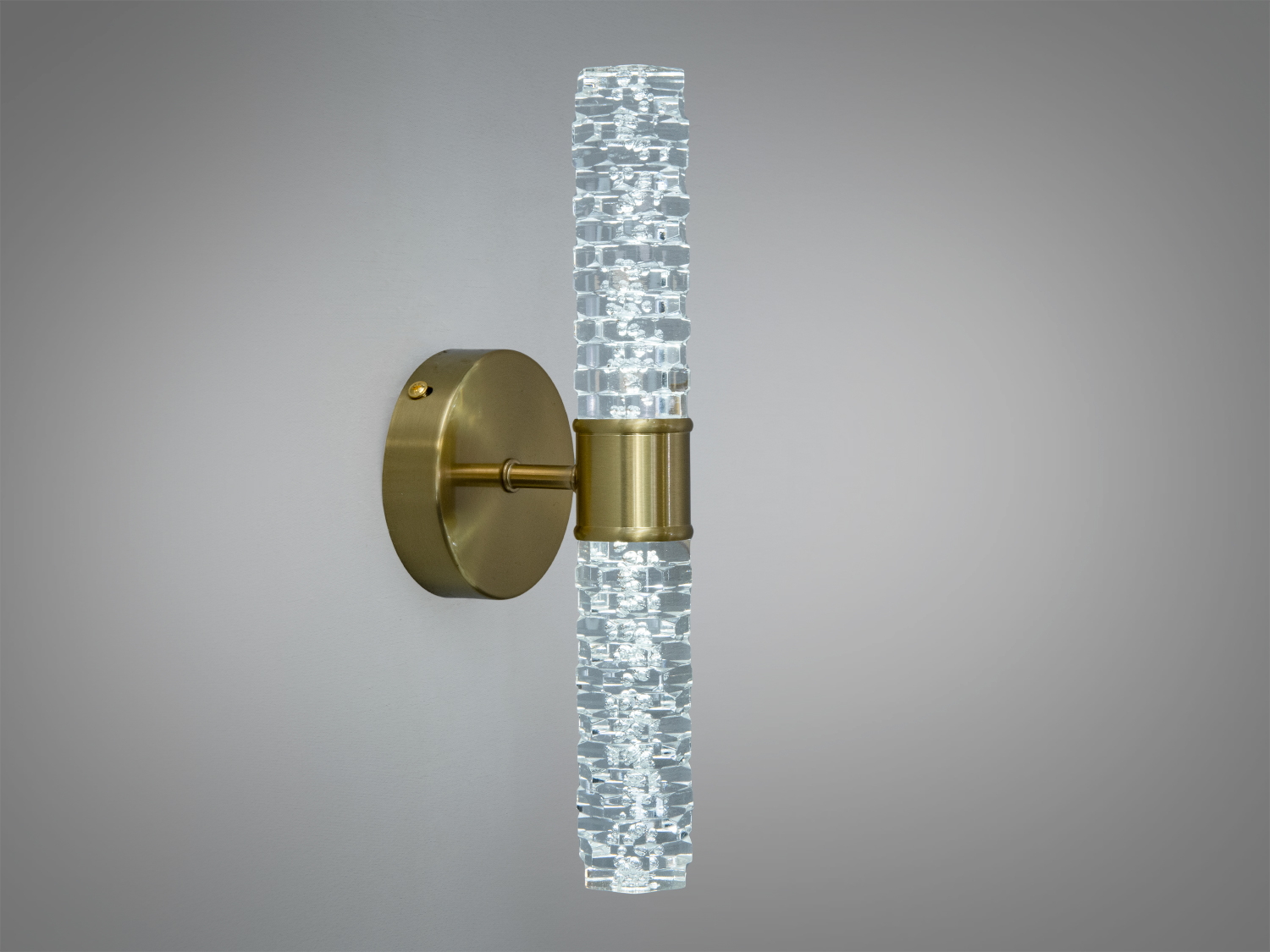 Латунний настінний світильник з циліндричним скляним плафоном, що створює м′яке освітлення. Підходить для ванних кімнат.