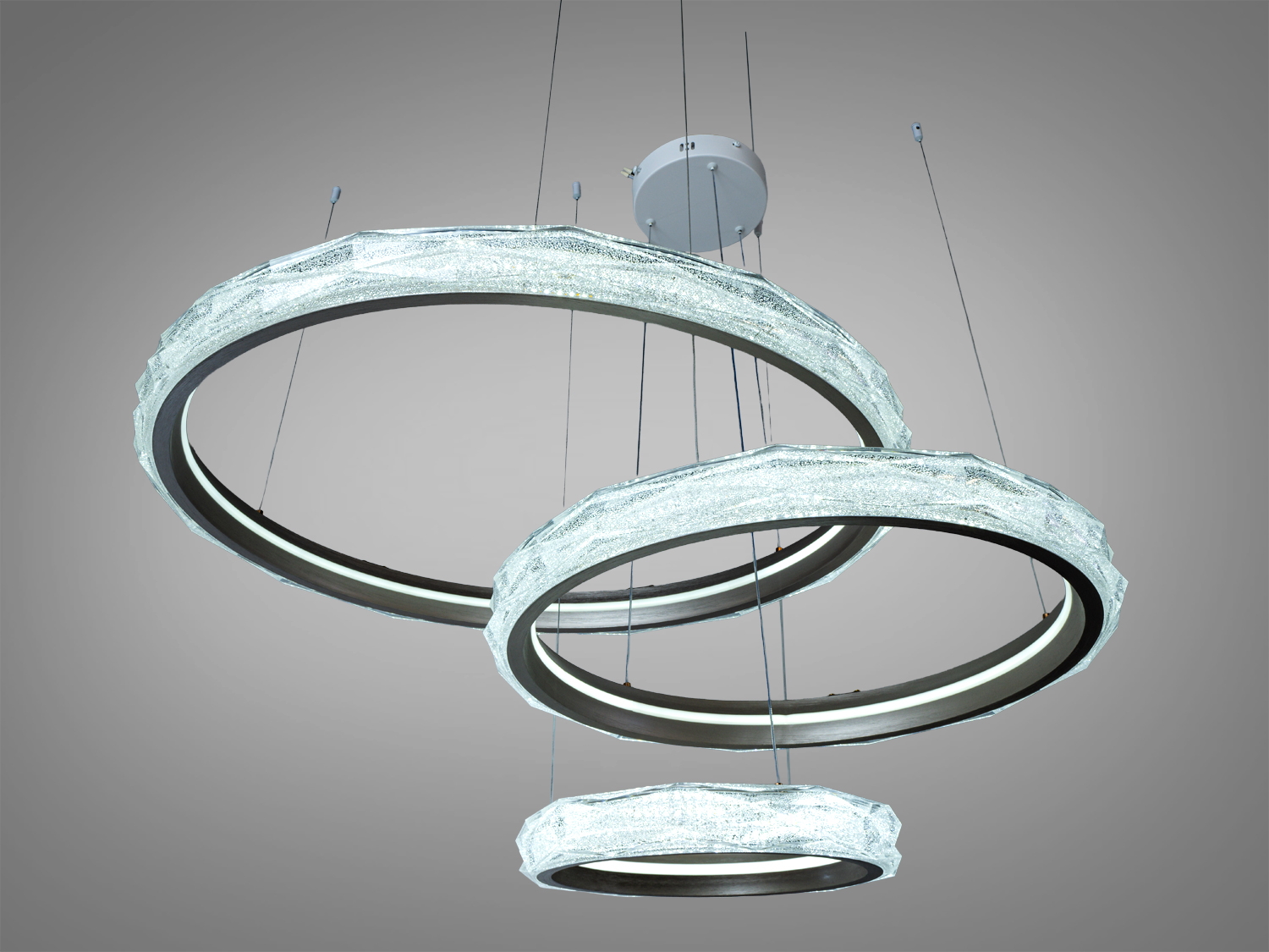 Світлодіодна люстра з трьома кільцями, підвішена на тросах. Виготовлена з металу, має текстуровану поверхню для стильного вигляду.