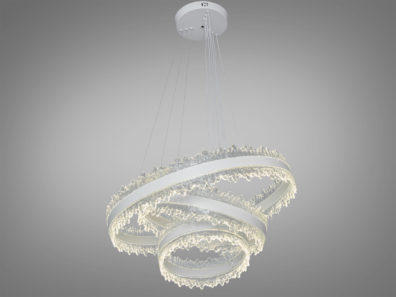 Люстра з трьома акриловими кільцями, підвішена на тонких дротах до стелі, створює сучасний стиль в інтер′єрі.