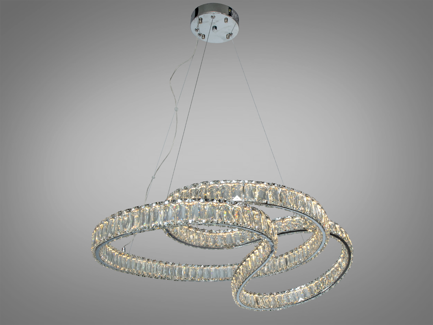 Люстра з трьома переплетеними кільцями з кристалів, підвішена на тонких тросах, створює ефект легкості в сучасному інтер′єрі.