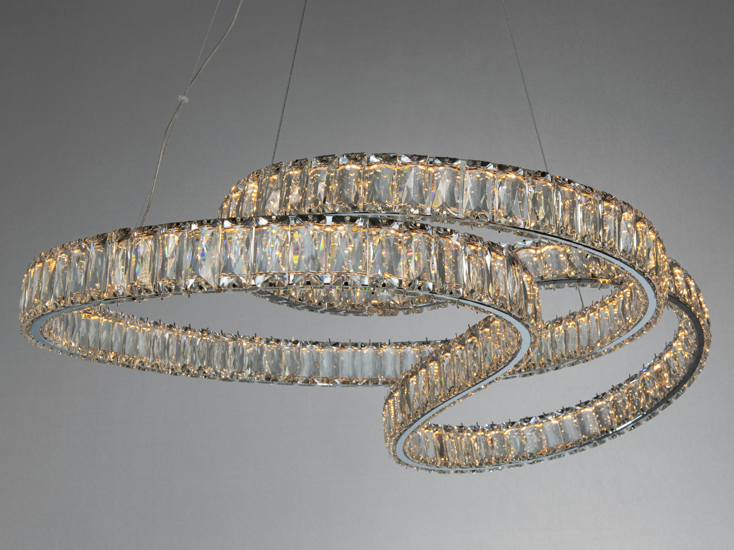 Кристалічна люстра з трьома кільцями, що переплітаються, забезпечує рівномірне освітлення завдяки LED-лампам, ідеальна для вітальні.